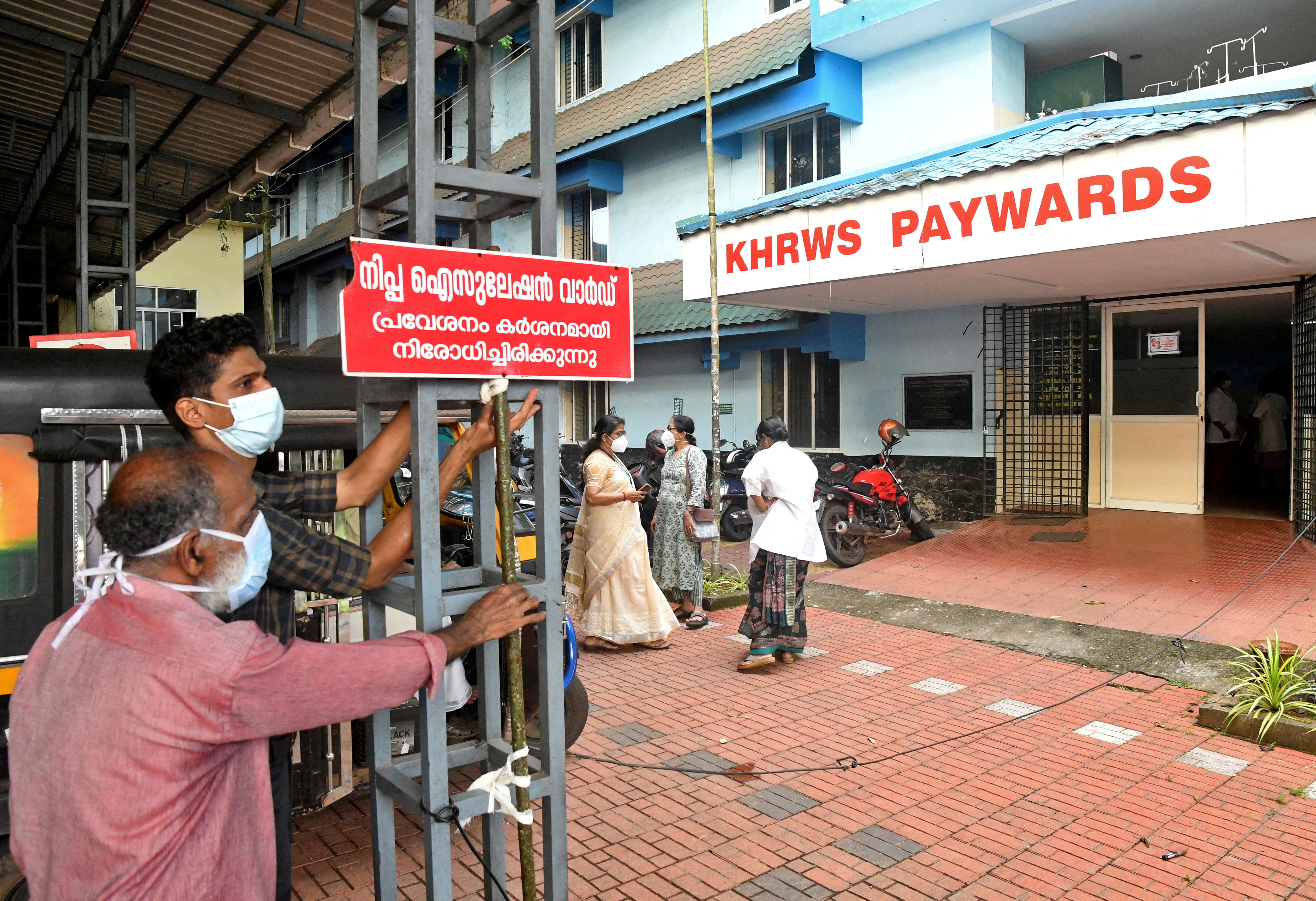 Staff install a sign reading "Nipah isolation ward, entry strictly prohibited" at a hospital where a ward is being prepared for suspected Nipah virus patients in Kozhikode