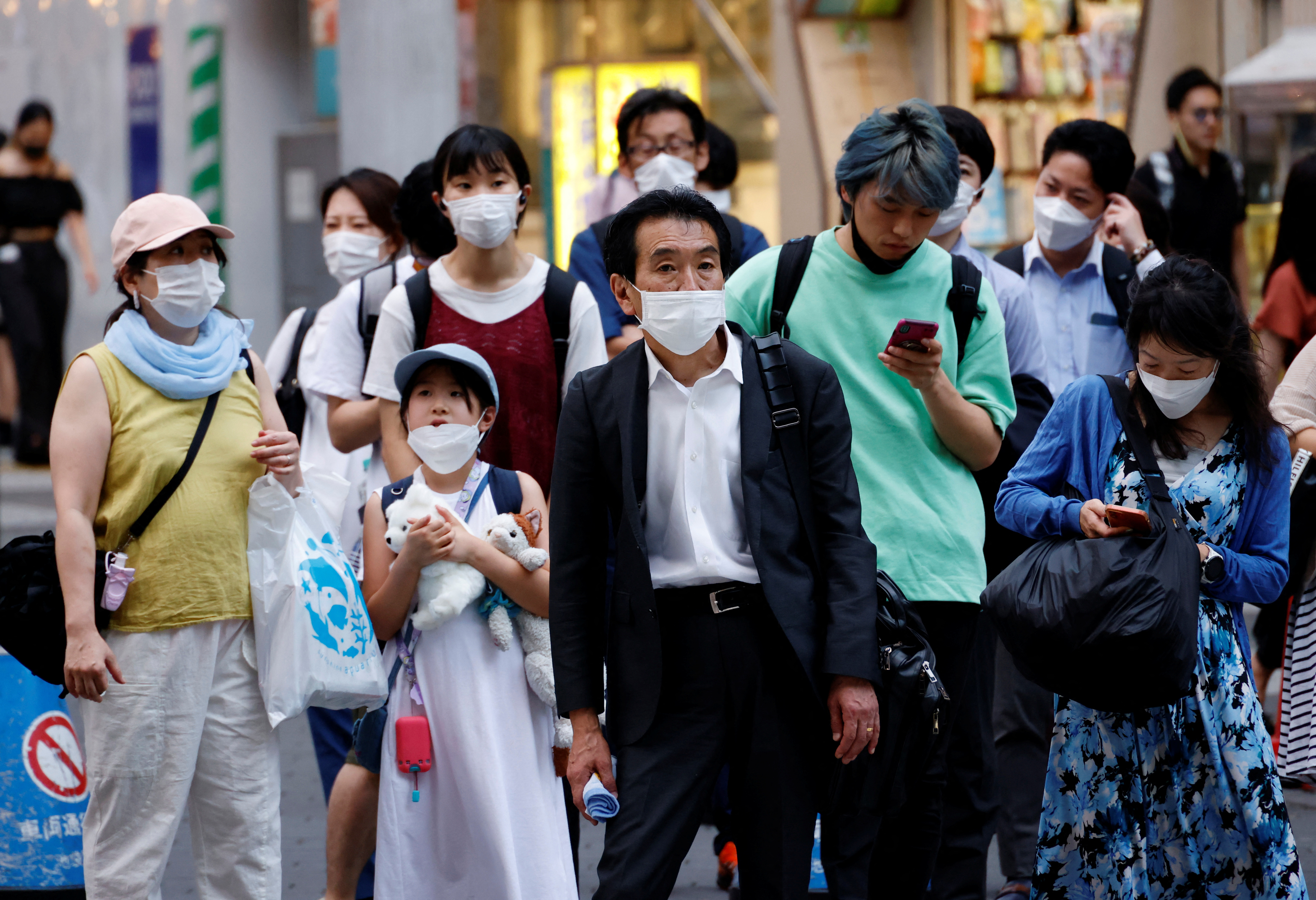 People wearing protective masks amid the coronavirus disease (COVID-19) outbreak, stand in front of cross walk in Tokyo