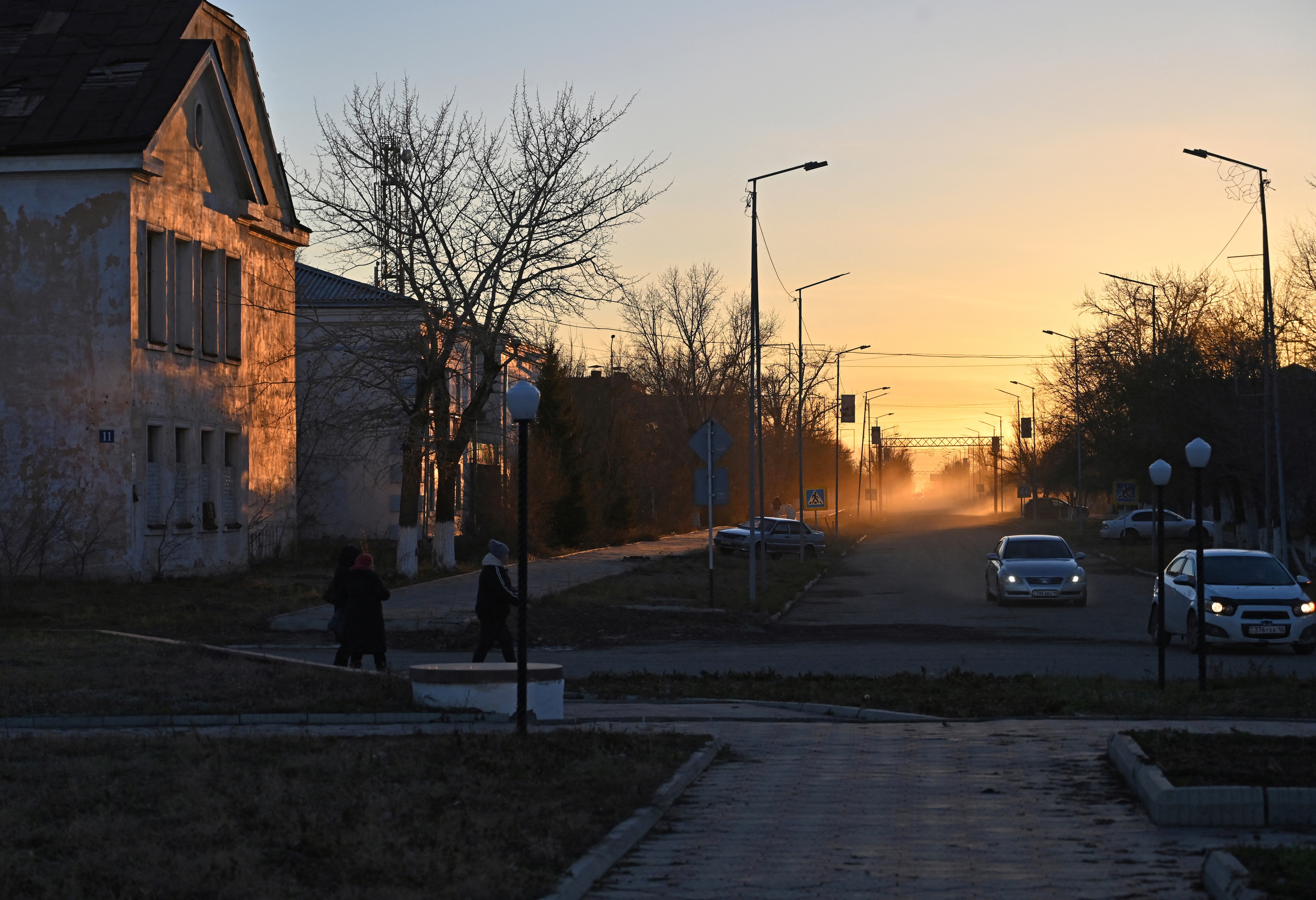 People walk along a street during sunset in Kurchatov
