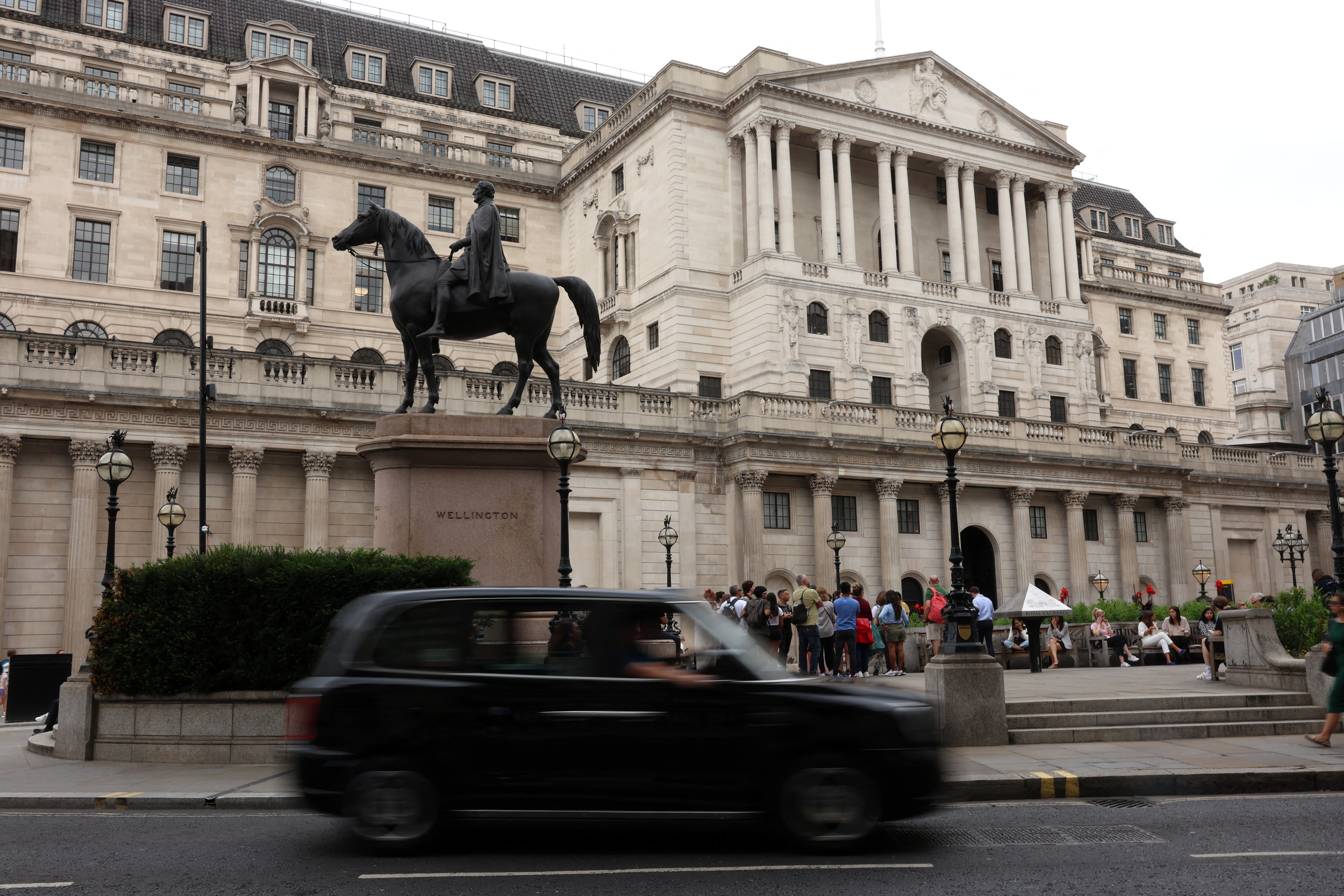 A black cab drives past the Bank of England in the financial district of London