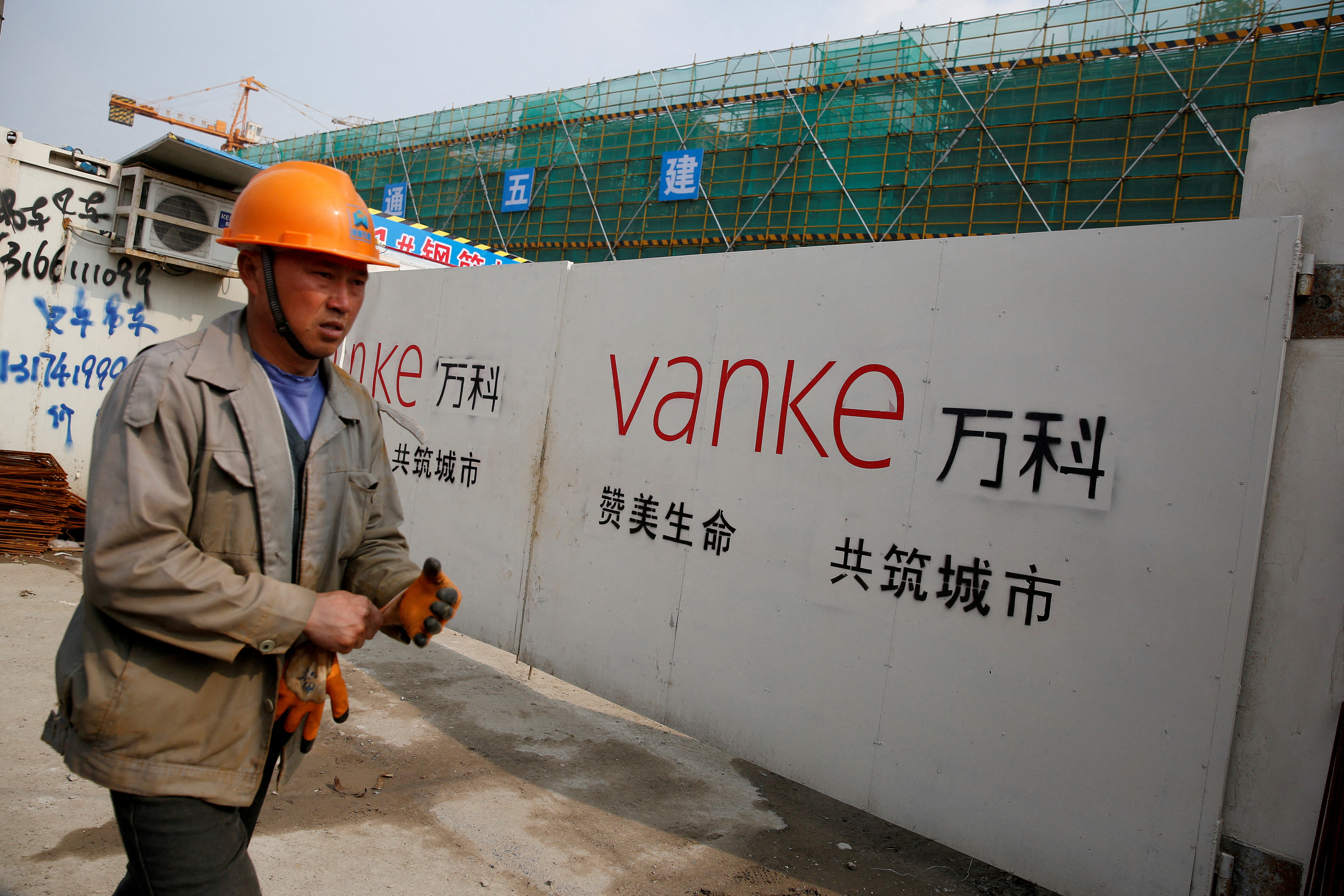 FILE PHOTO: A person walks past by a gate with a sign of Vanke at a construction site in Shanghai