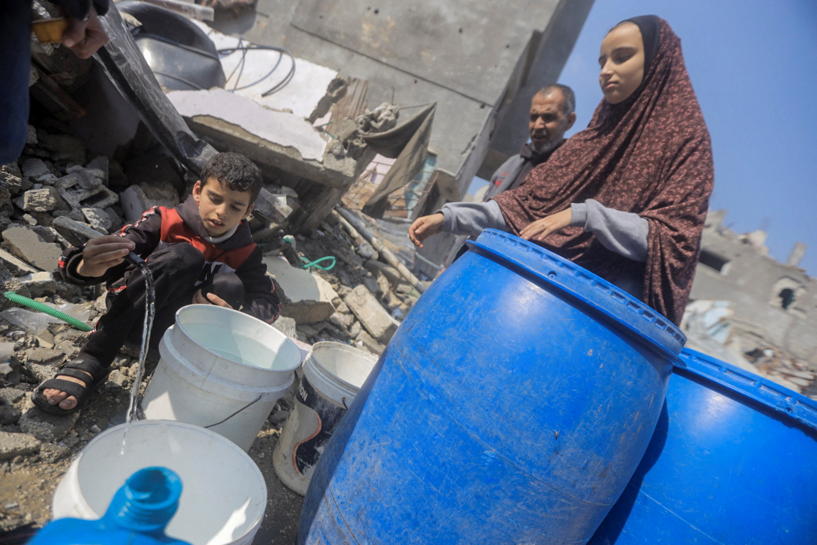 Palestinians collect water from a house destroyed by an Israeli strike, in Jabalia refugee camp in the northern Gaza Strip