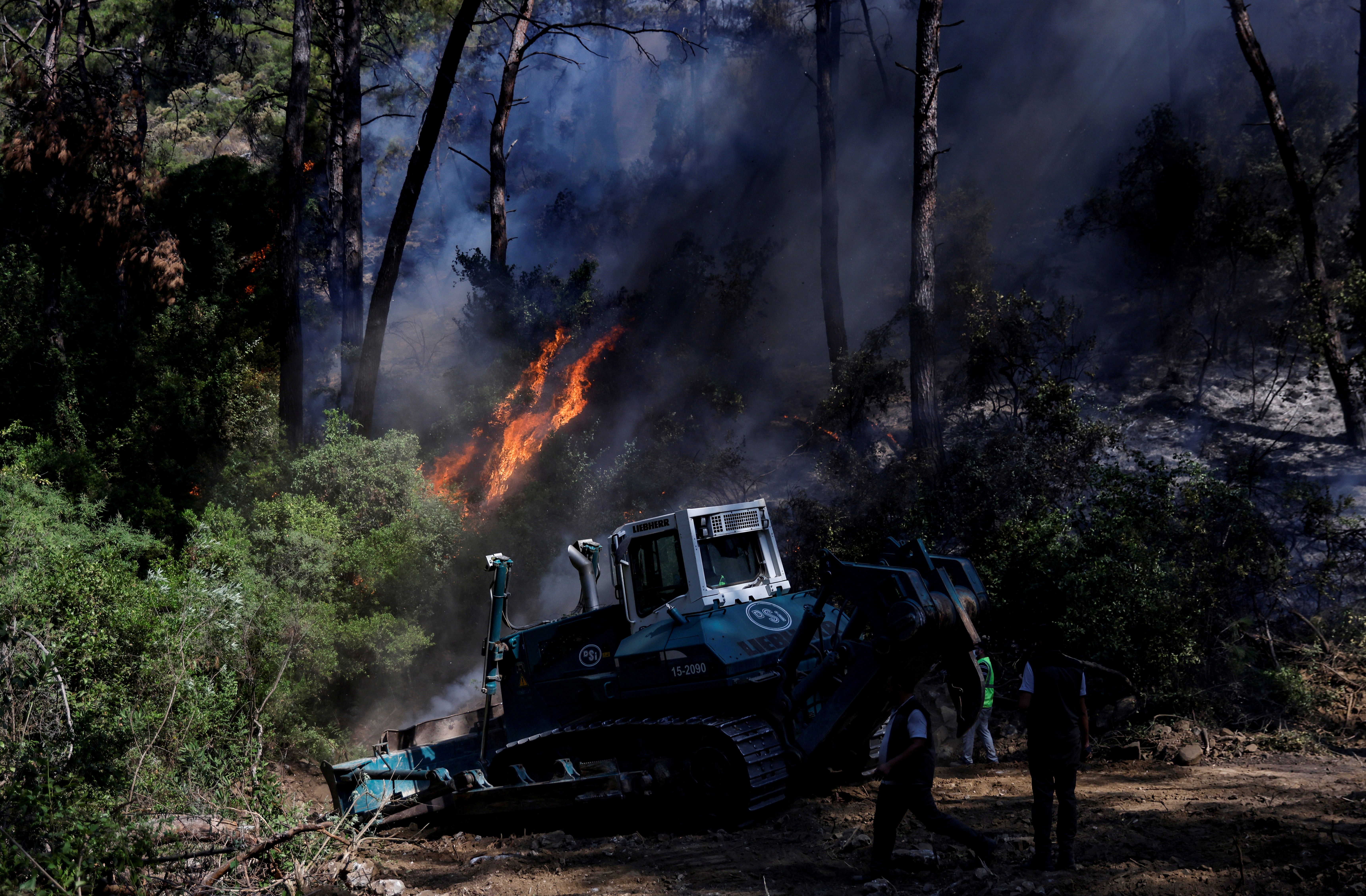 A bulldozer opens the way to firefighters to help them to extinguish a wildfire near Marmaris, Turkey, August 2, 2021. REUTERS/Umit Bektas     TPX IMAGES OF THE DAY