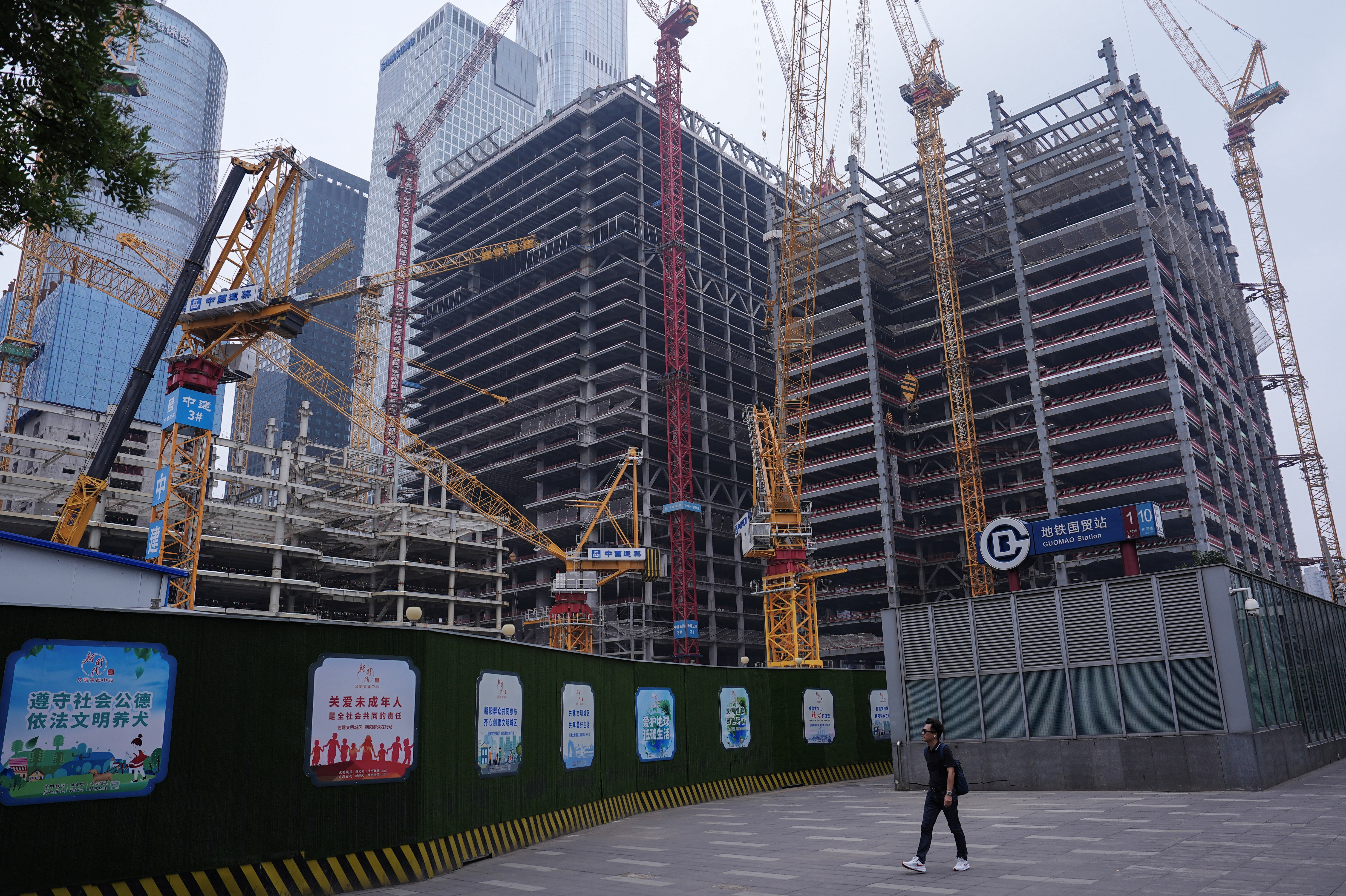 Person walks past a construction site in Beijing's Central Business District (CBD)
