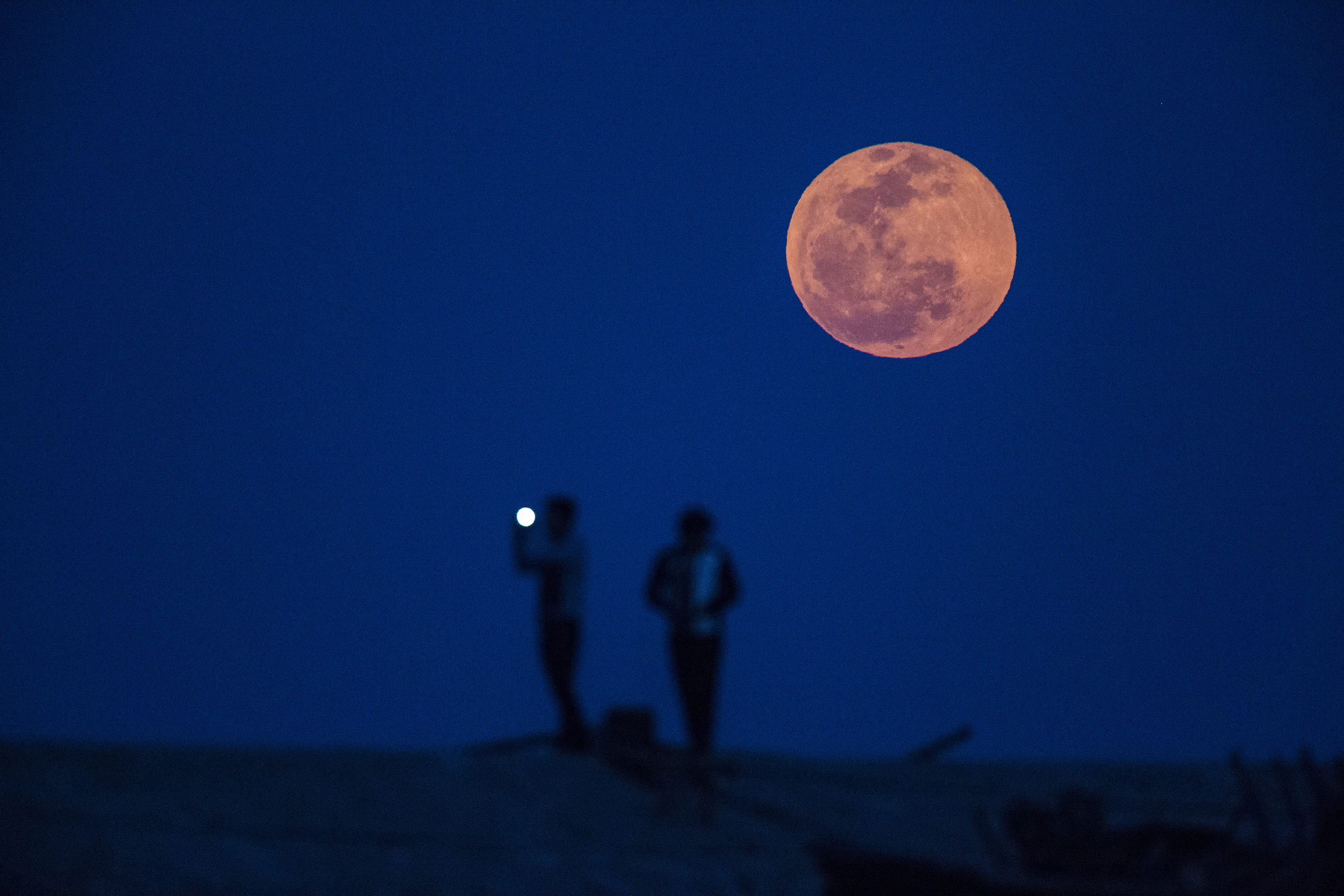 A man takes a picture during moon rise in a suburb of Shanghai