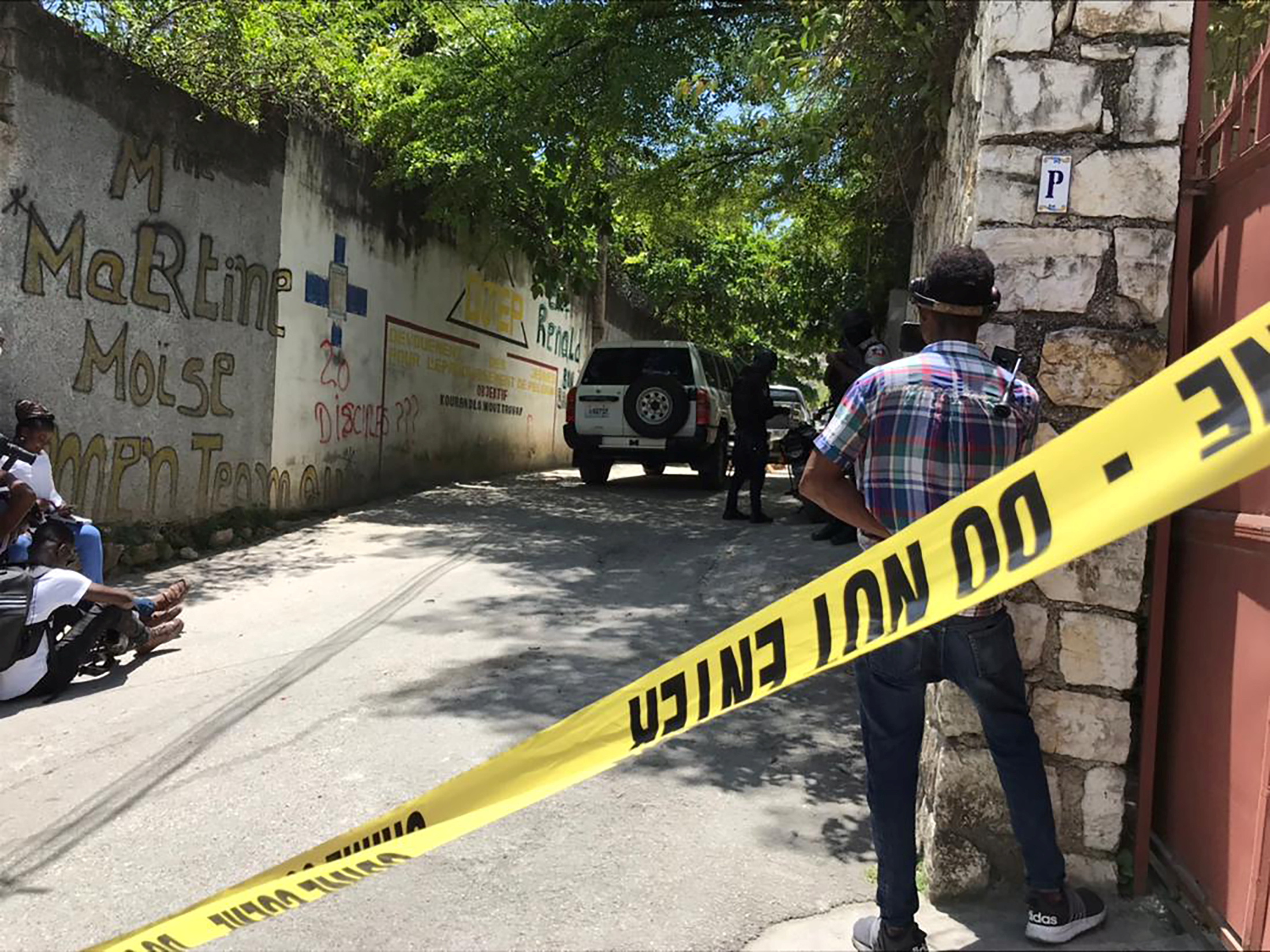 Journalists stand next to a yellow police cordon near the residence of Haiti's President Jovenel Moise after he was shot dead by unidentified attackers, in Port-au-Prince