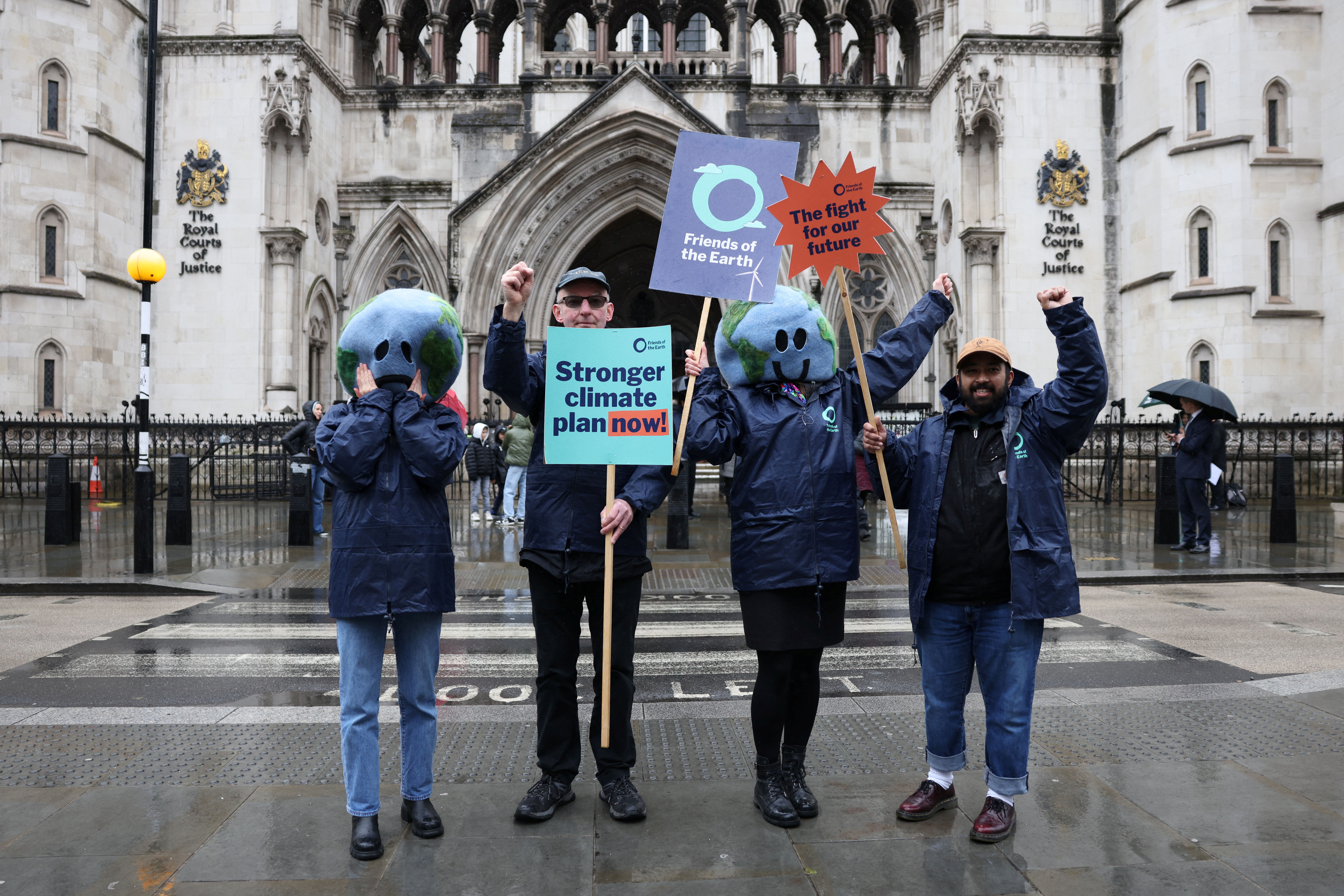 Environmental campaigners hold placards outside the High Court in London