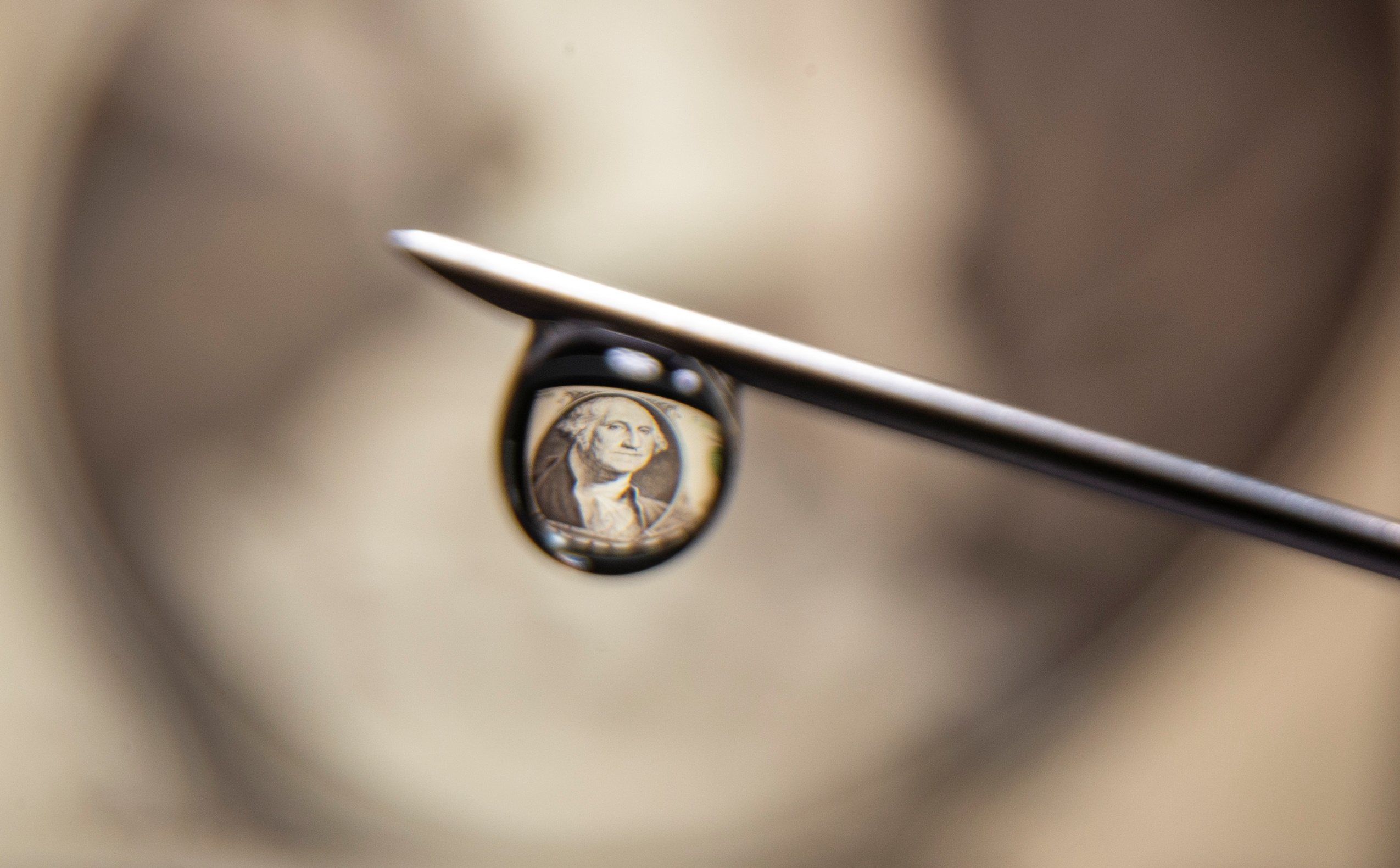 U.S. one dollar banknote is reflected in a drop on a syringe needle in this illustration photo