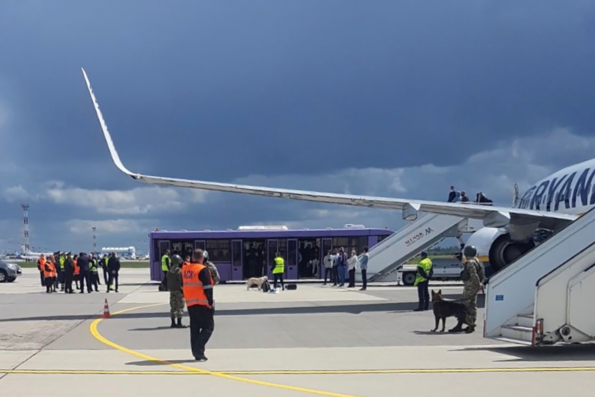 Airport personnel and security forces are seen on the tarmac in front of a Ryanair flight which was forced to land in Minsk