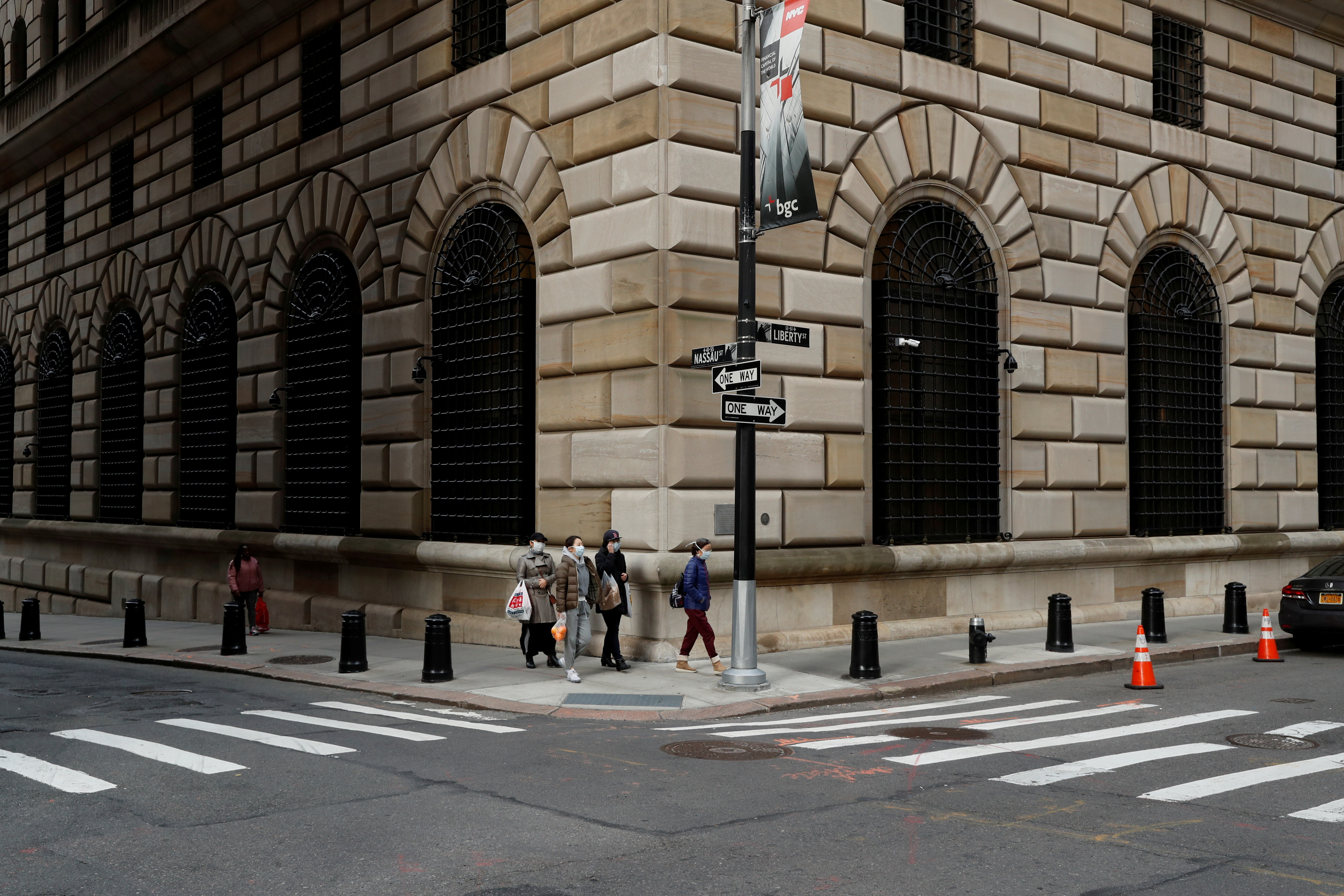 People walk wearing masks outside The Federal Reserve Bank of New York in New York
