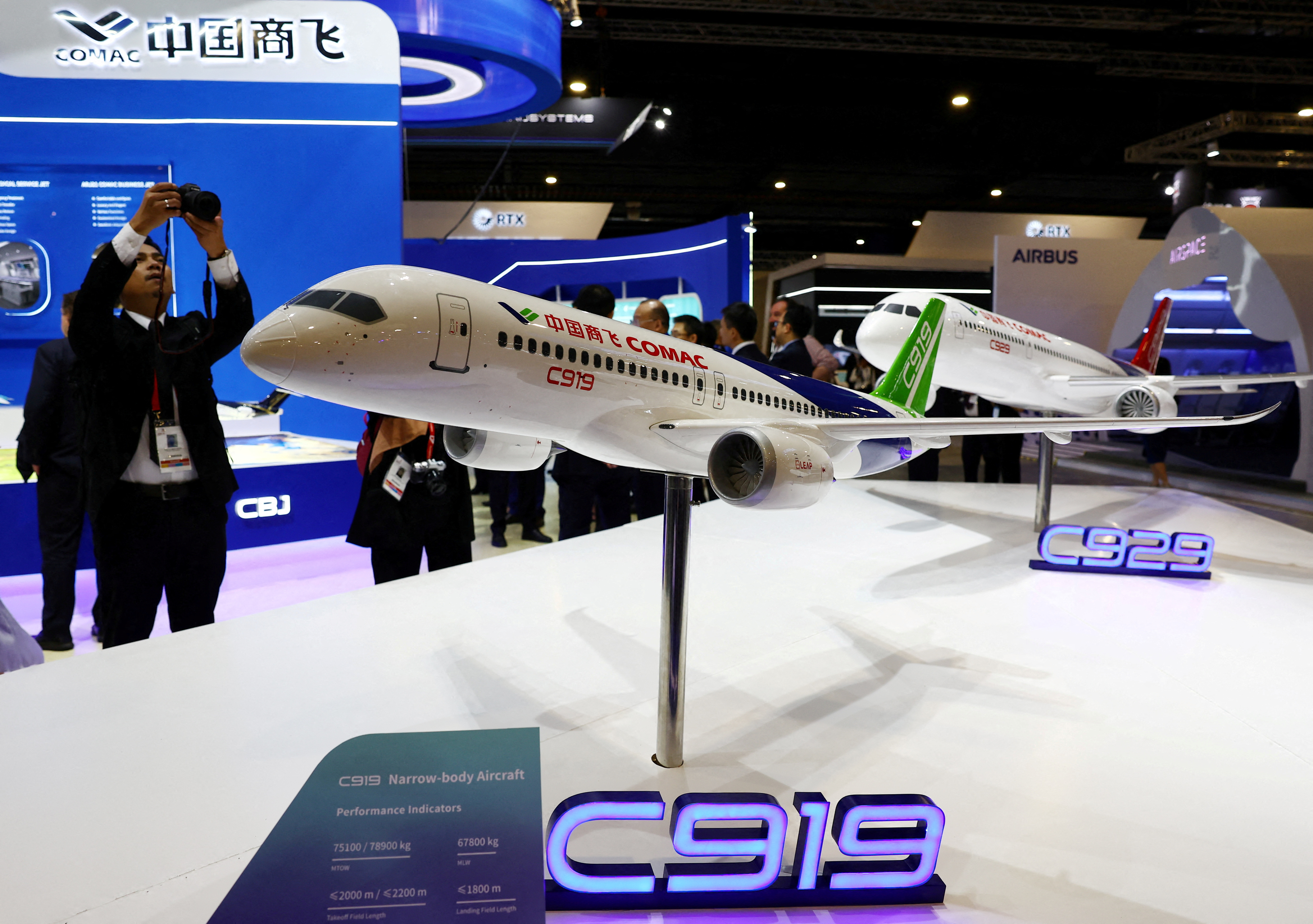 People take photos of a model of the Comac C919 plane during the Singapore Airshow at Changi Exhibition Centre in Singapore