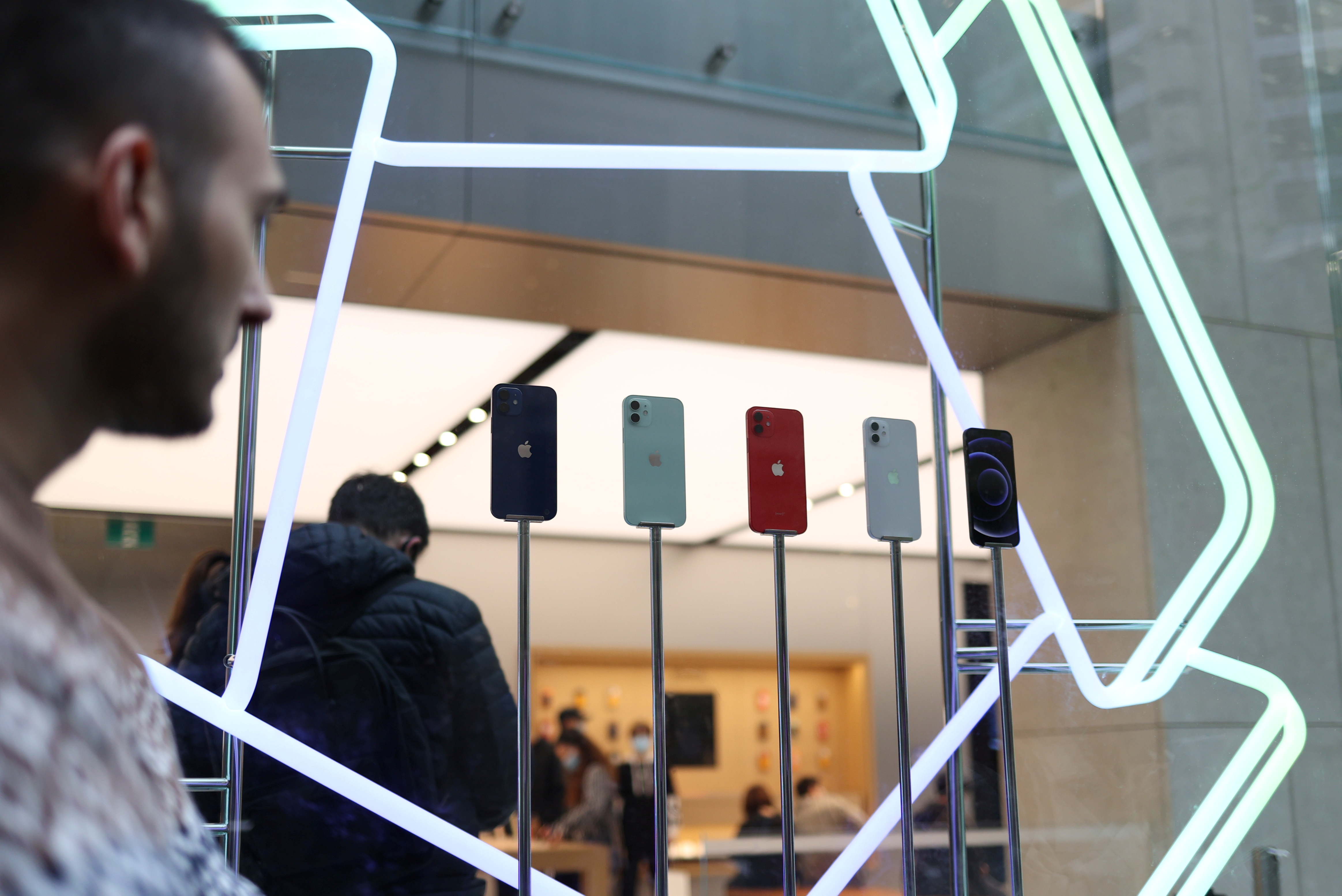 A shopper looks at an iPhone 12 display while waiting in line to enter an Apple Store in the city centre as the state of New South Wales continues to report low case numbers of the coronavirus disease (COVID-19) in Sydney, Australia, October 26, 2020. REUTERS/Loren Elliott