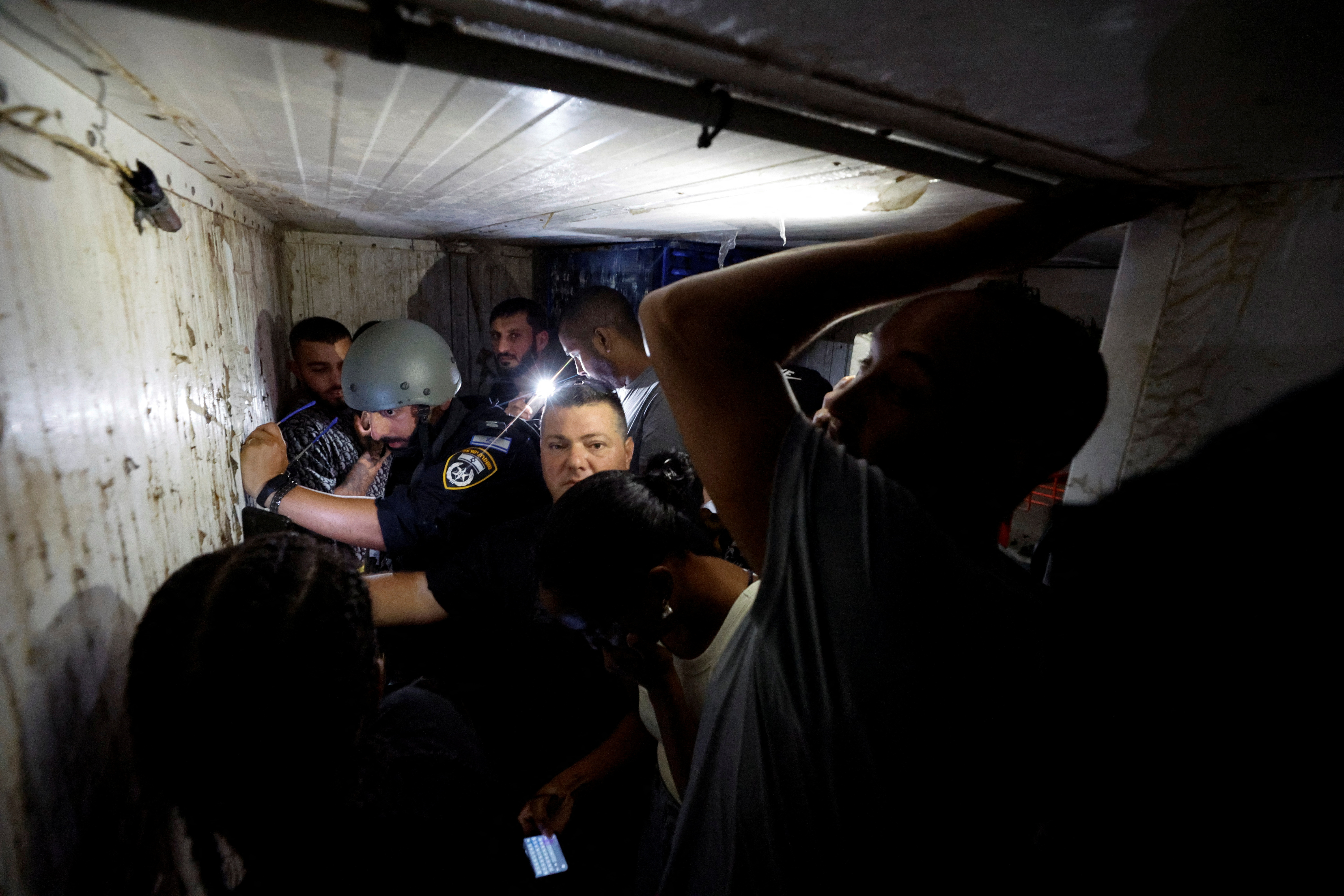 Israelis take cover in a bomb shelter while sirens sound as rockets from Gaza are launched towards Israel, in Ashkelon