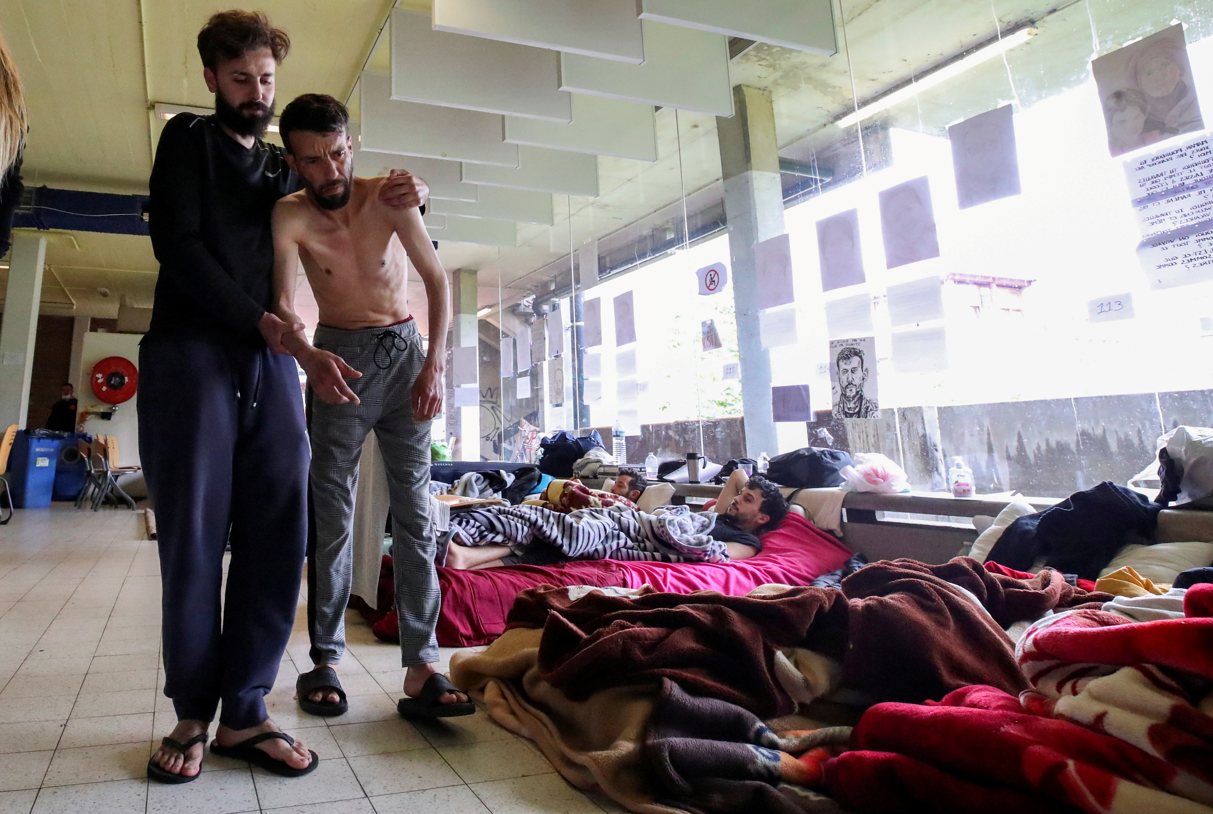 Youssef Bouzidi, un solicitante de asilo marroquí que solicita ser regularizado polo goberno belga para ter acceso á asistencia sanitaria e que está en folga de fame durante máis dun mes, está axudado por unha persoa nunha habitación do campus da universidade belga ULB, onde centos de migrantes están en folga de fame, en Bruxelas, Bélxica, o 29 de xuño de 2021. REUTERS / Yves Herman