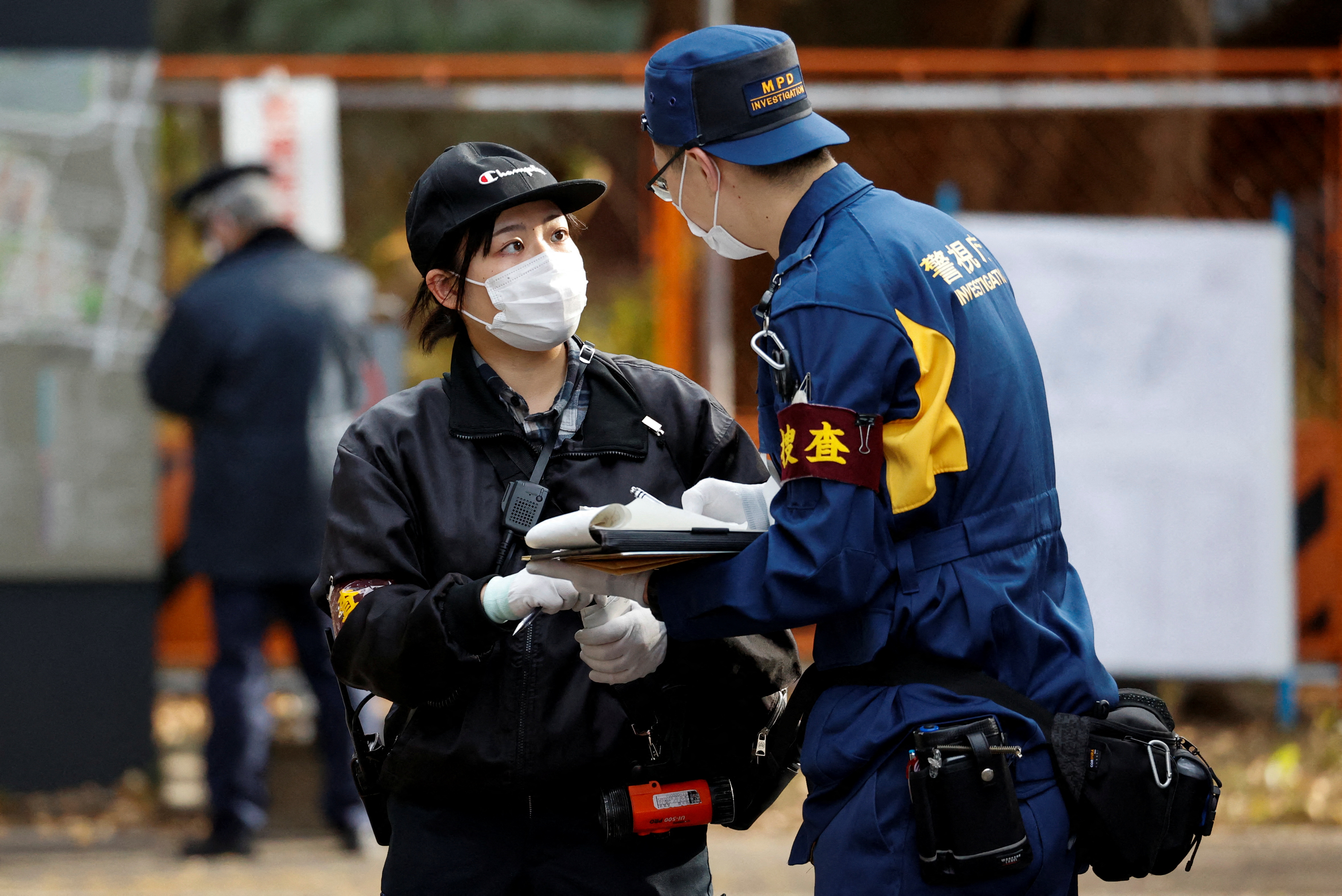 A police investigator speaks to another person at the site where a stabbing incident happened at an entrance gate of Tokyo University in Tokyo, Japan January 15, 2022. REUTERS/Issei Kato