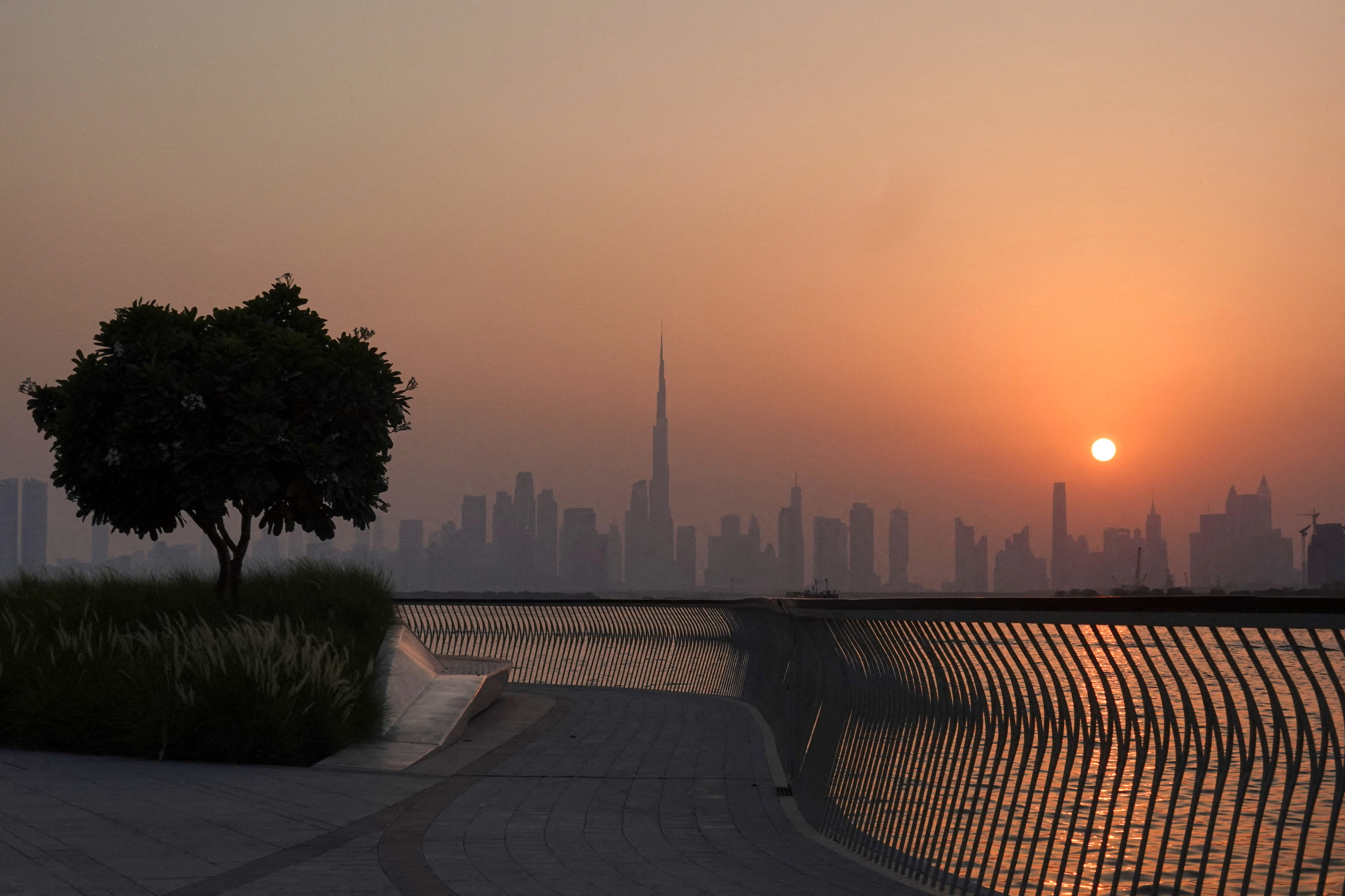 The Burj Khalifa building peaks through the skyline as the sun sets over Dubai