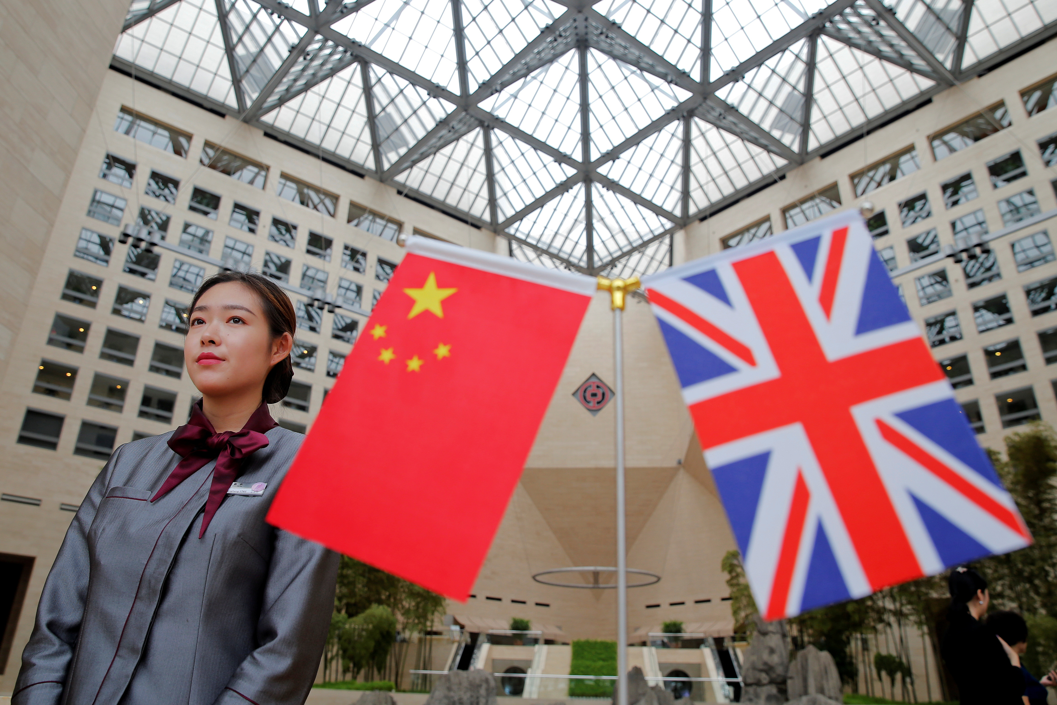 A member of staff waits behind flags at the Bank of China head office building in Beijing