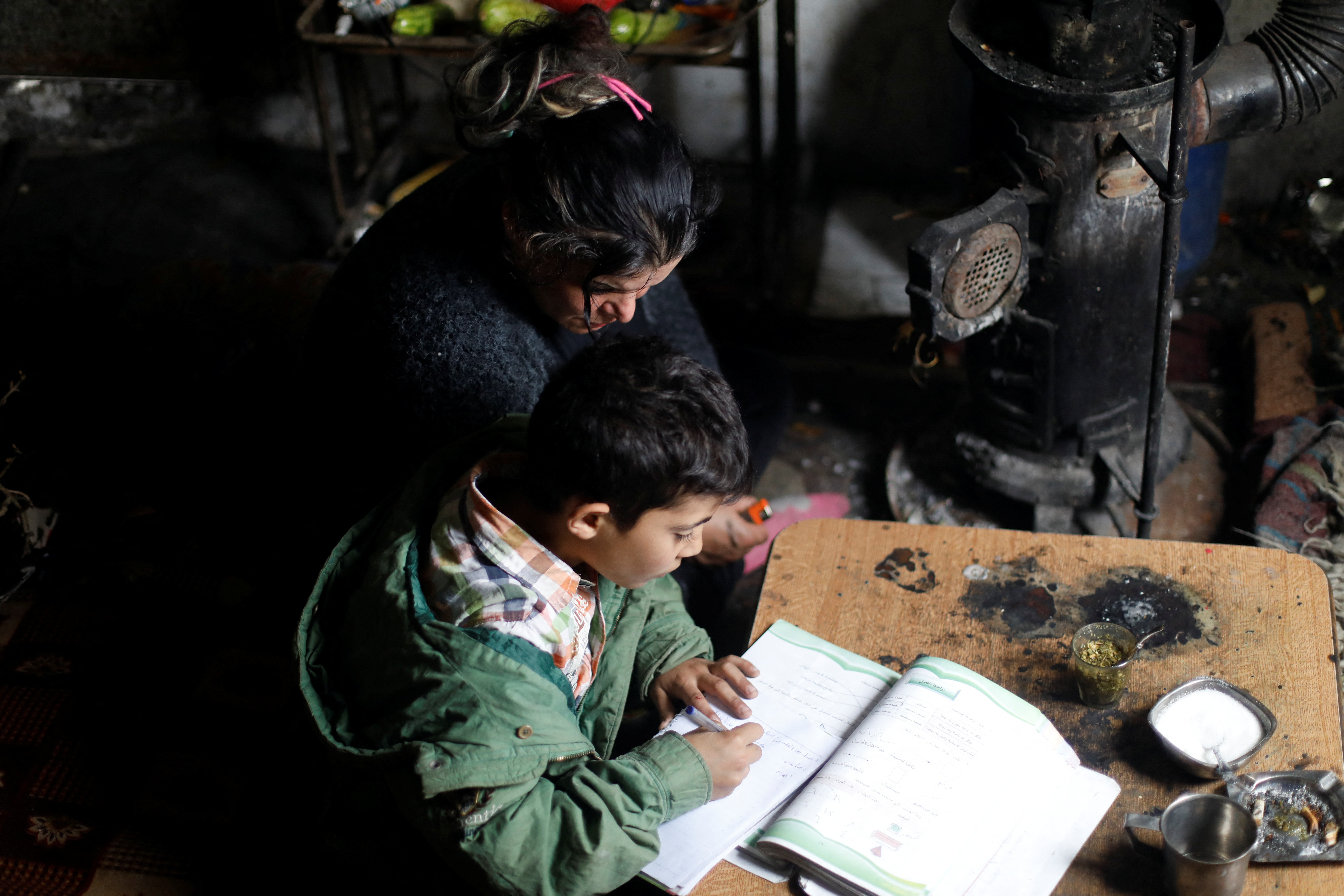 Ahlam Mohsin Warda helps her son with his studies at their home in Damascus