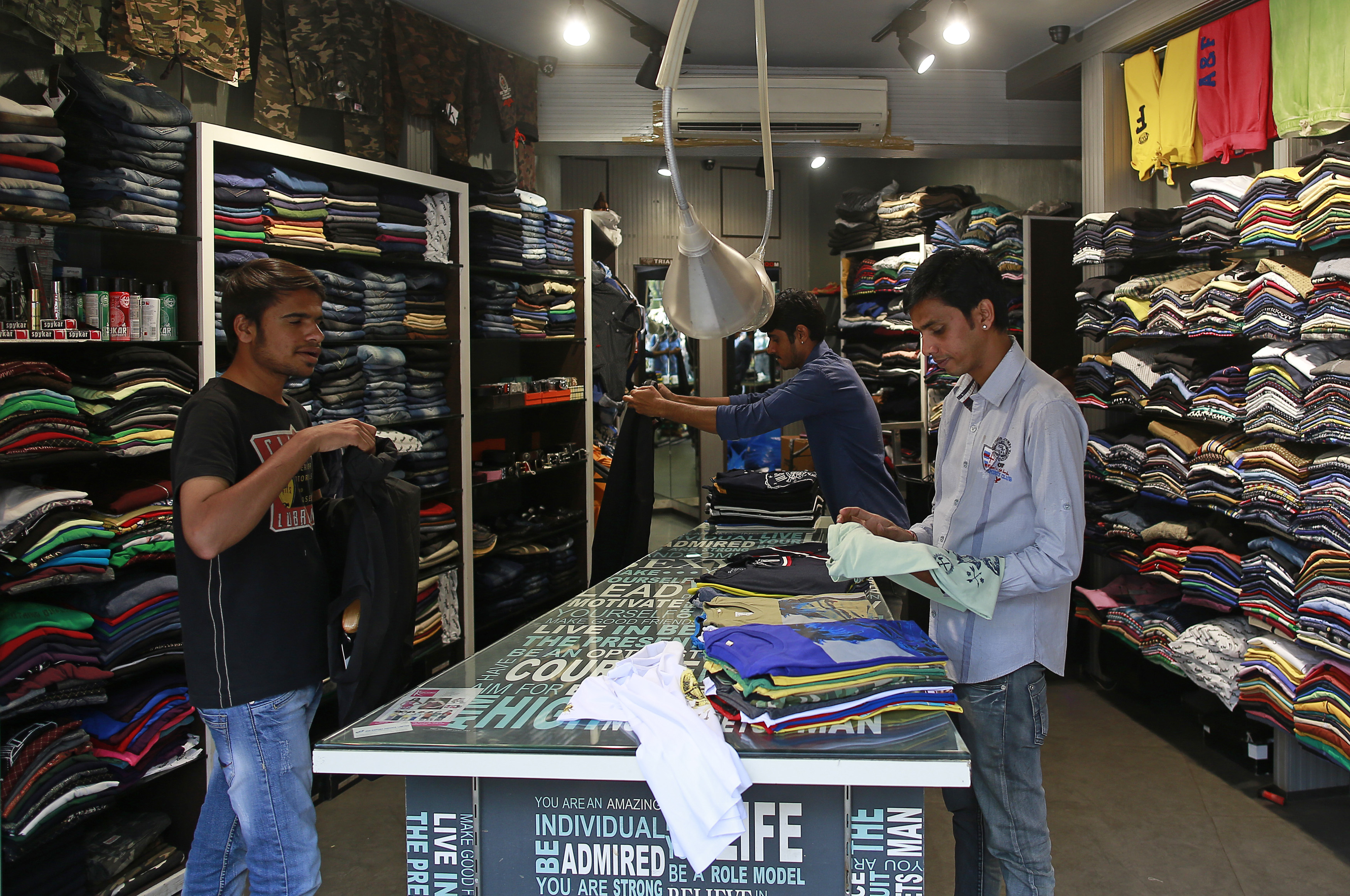 Salesmen fold shirts inside a clothes store at a market in Mumbai
