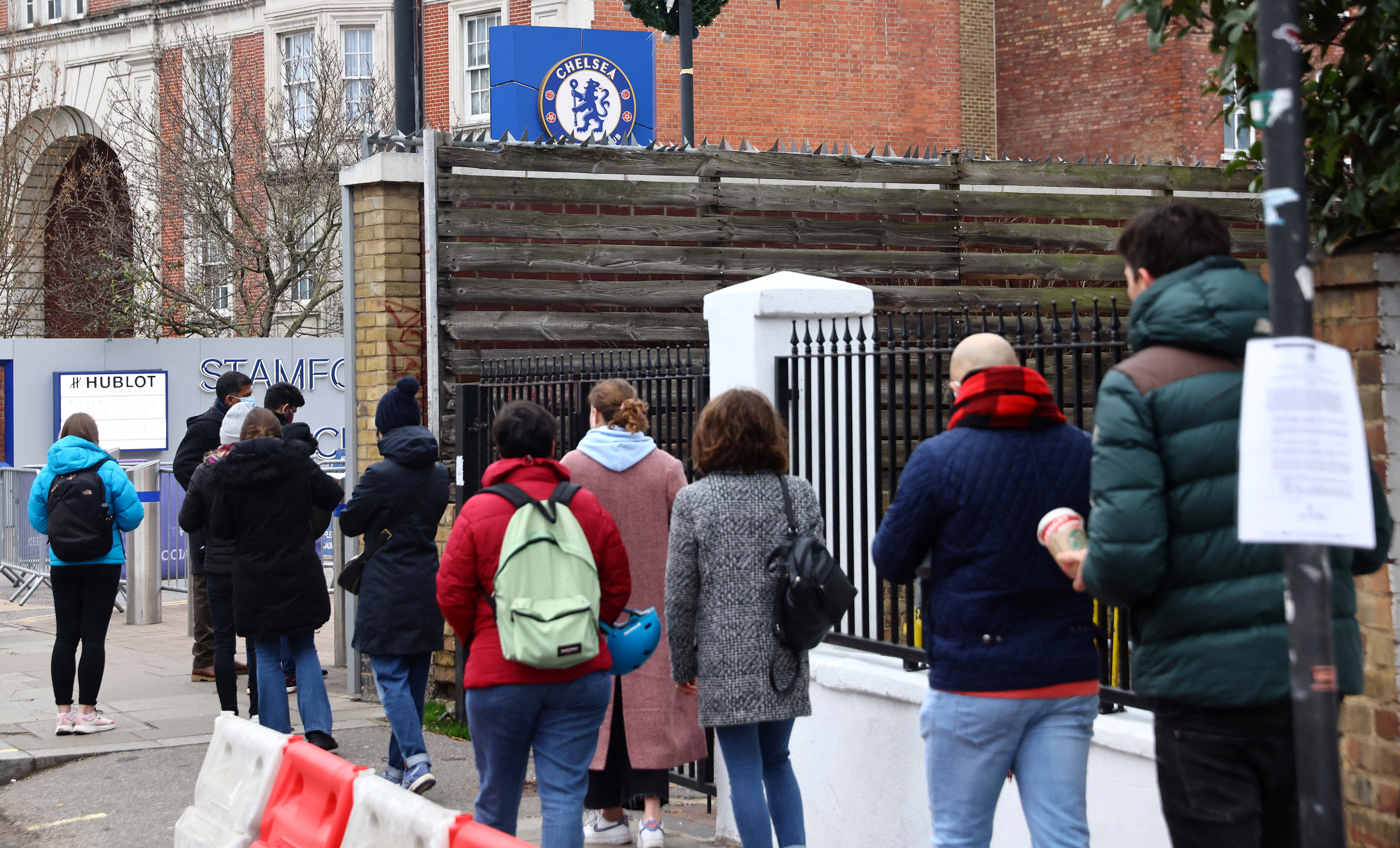 People queue for a booster dose outside COVID-19 pop-up vaccination centre at Chelsea football ground