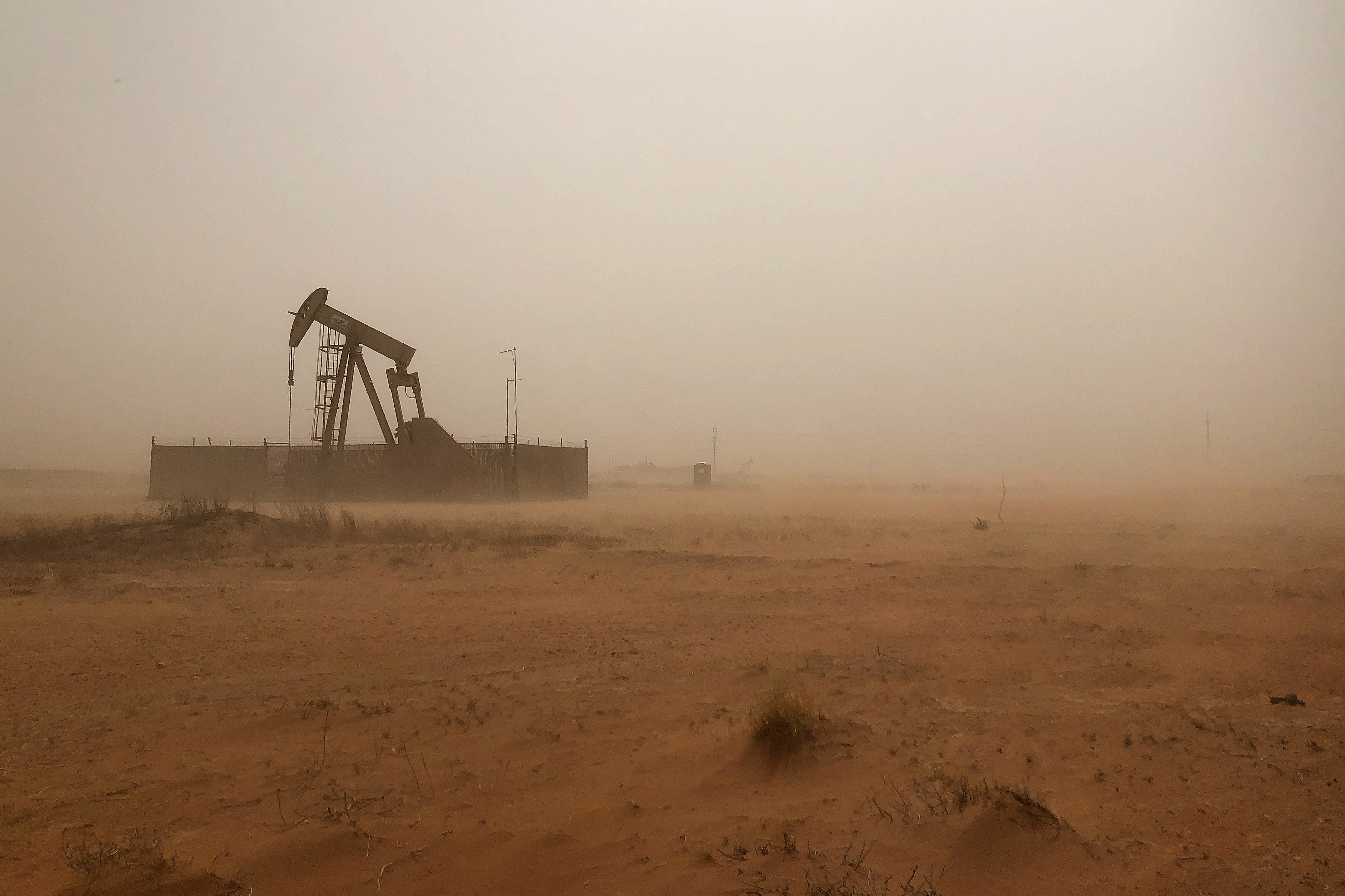 A pump jack lifts oil out of a well during a sandstorm in Midland