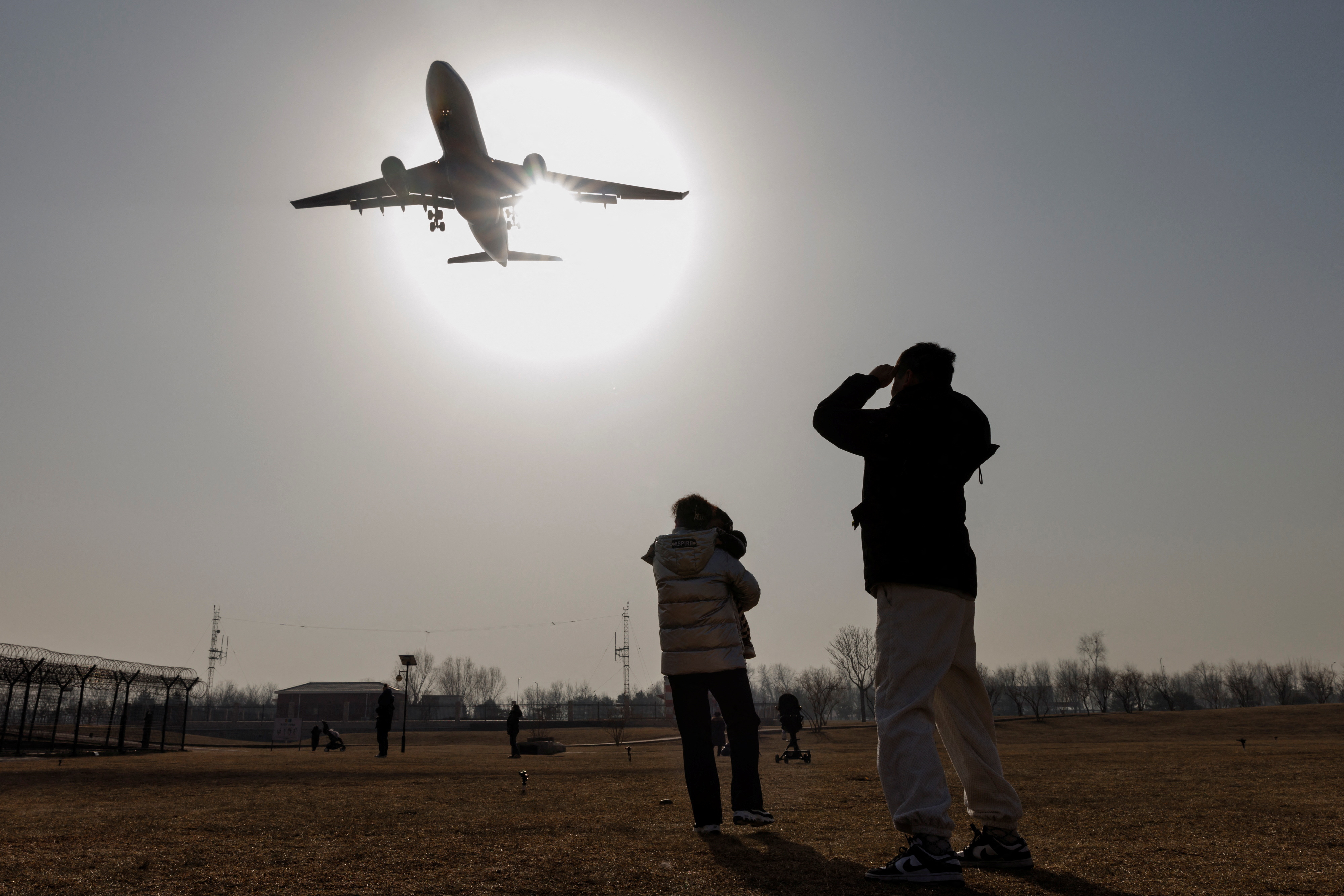 People watch a plane land at Beijing Capital International Airport as coronavirus disease (COVID-19) outbreaks continue in Beijing