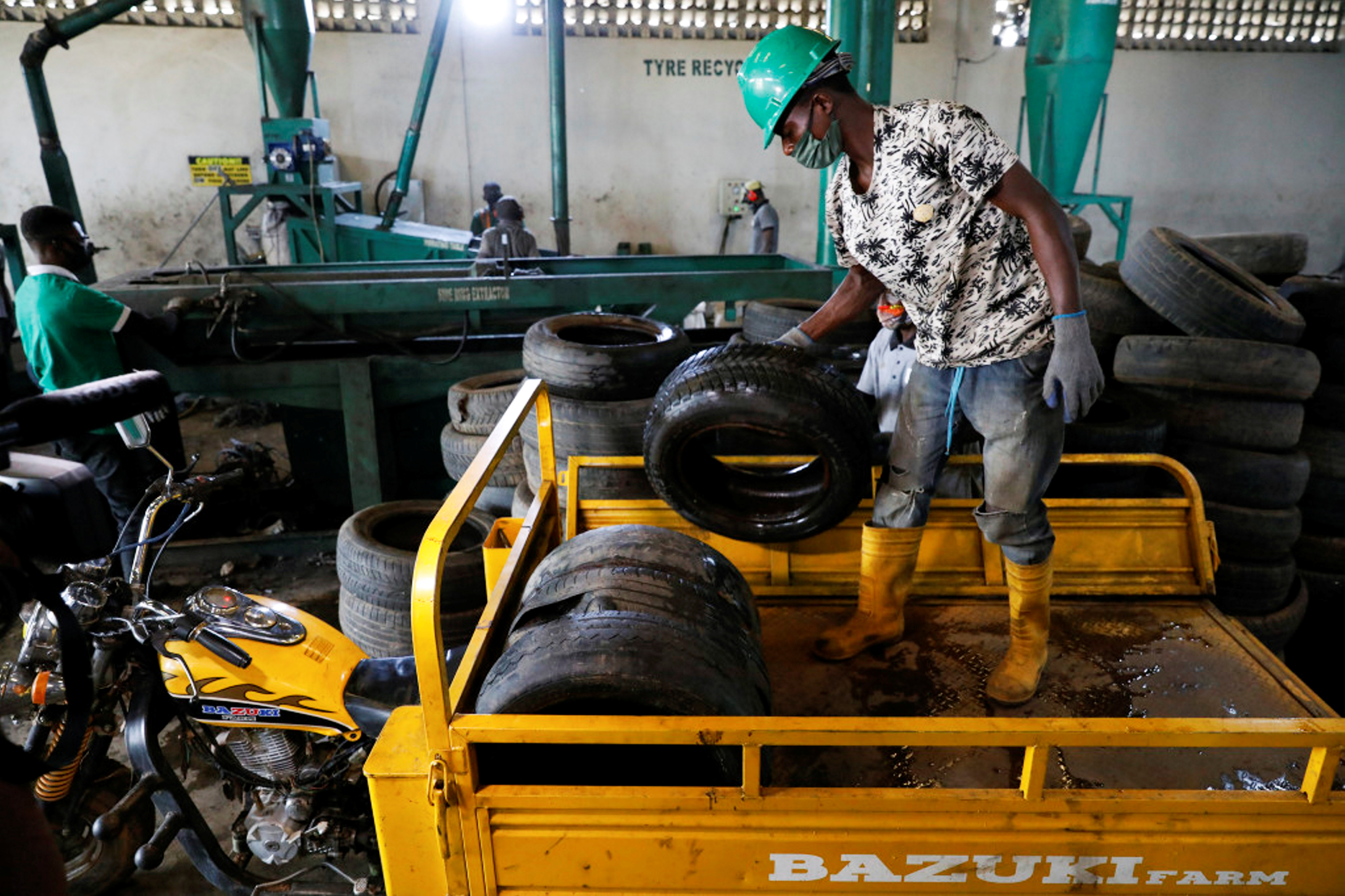 Worker offloads used car tyres from a cargo tricycle in preparation for recycling in Ibadan