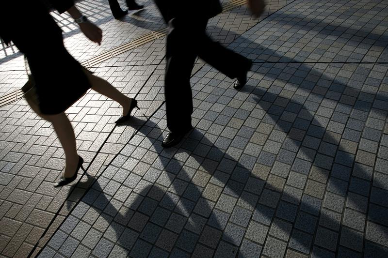 Pedestrians cast shadows as they walk on a street in Tokyo