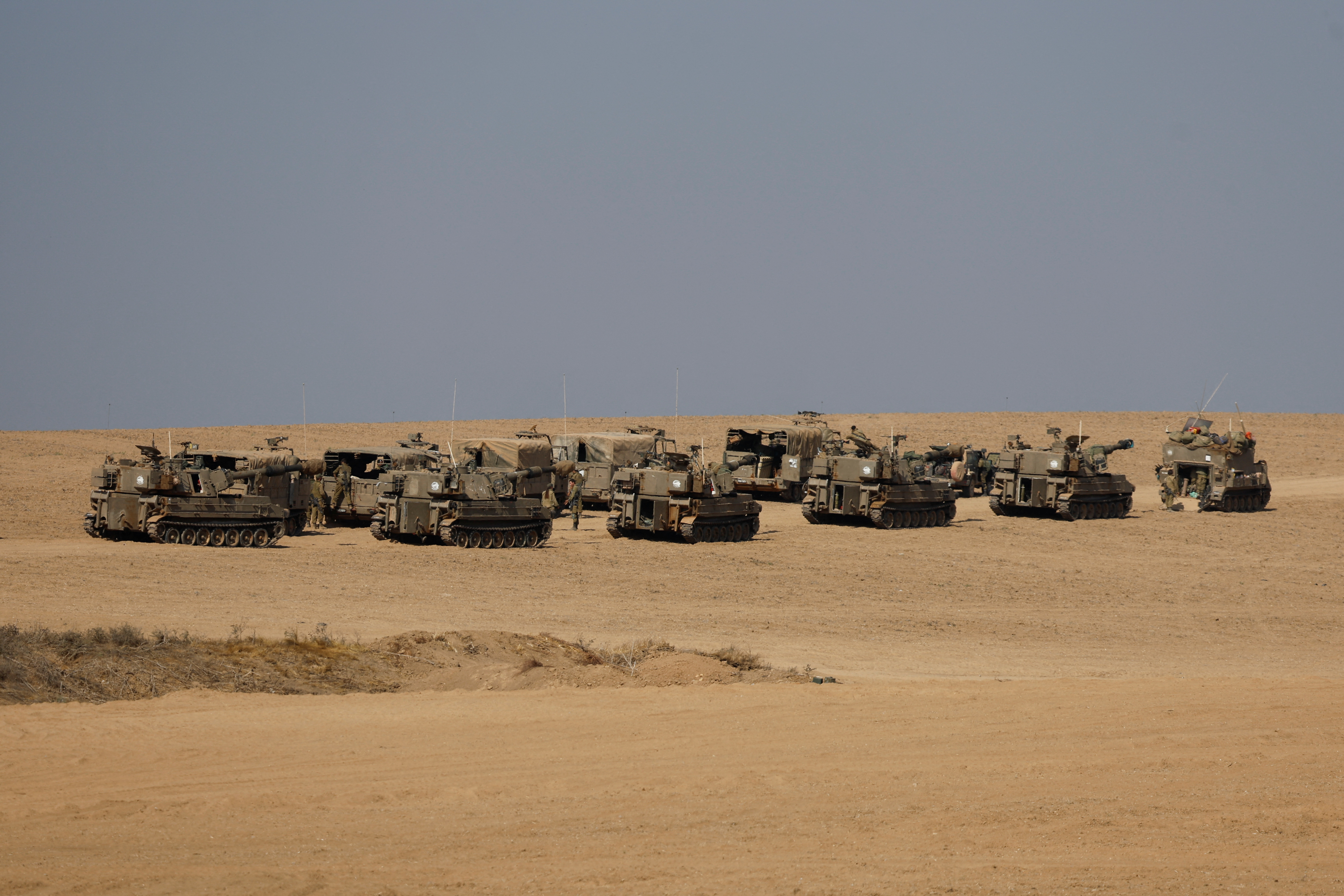 Israel soldiers stand next to artillery units near the Israeli side of the border between Israel and the Gaza Strip