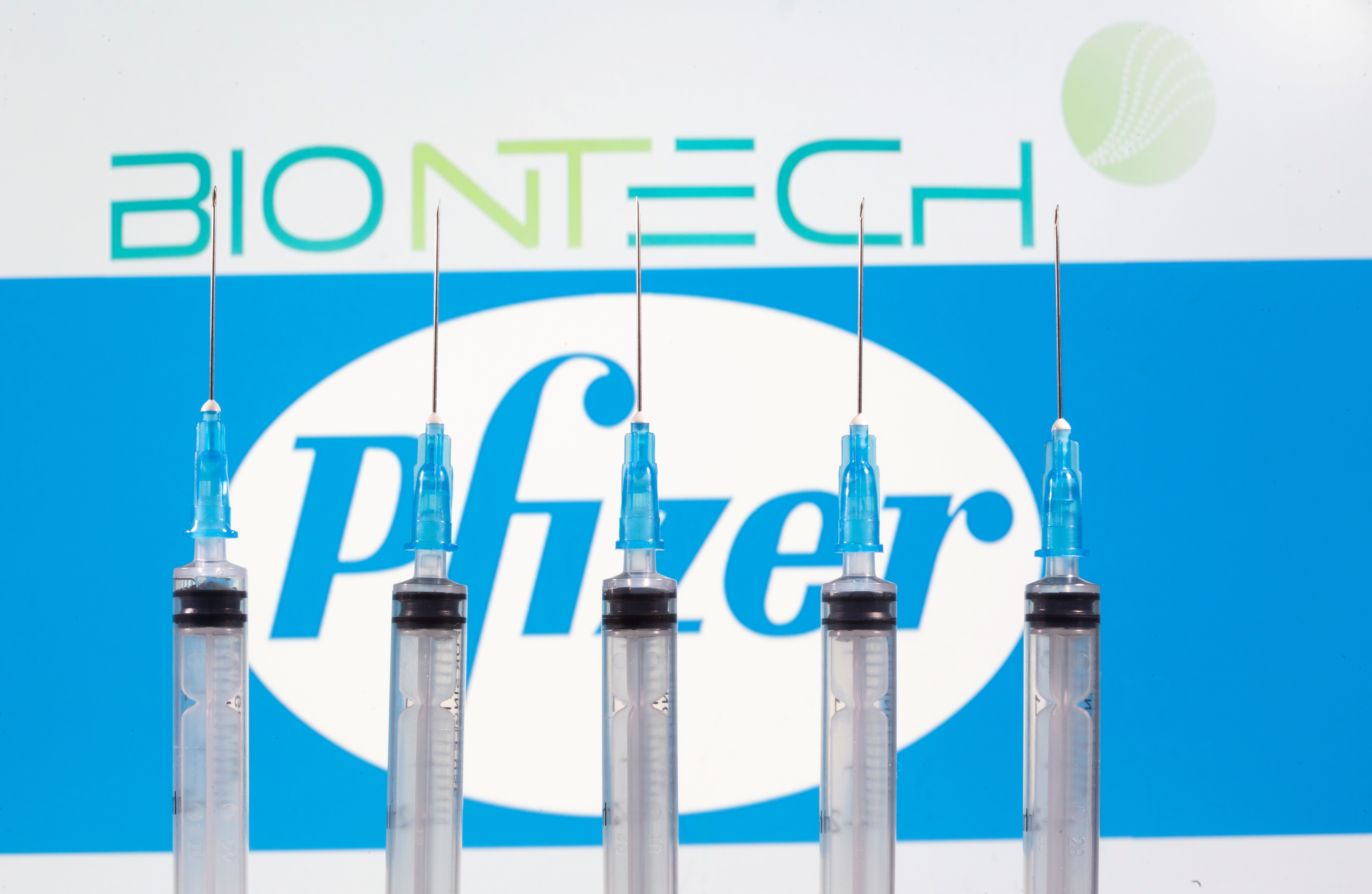 Syringes are seen in front of displayed Biontech and Pfizer logos in this illustration taken November 10, 2020. REUTERS/Dado Ruvic/Illustration