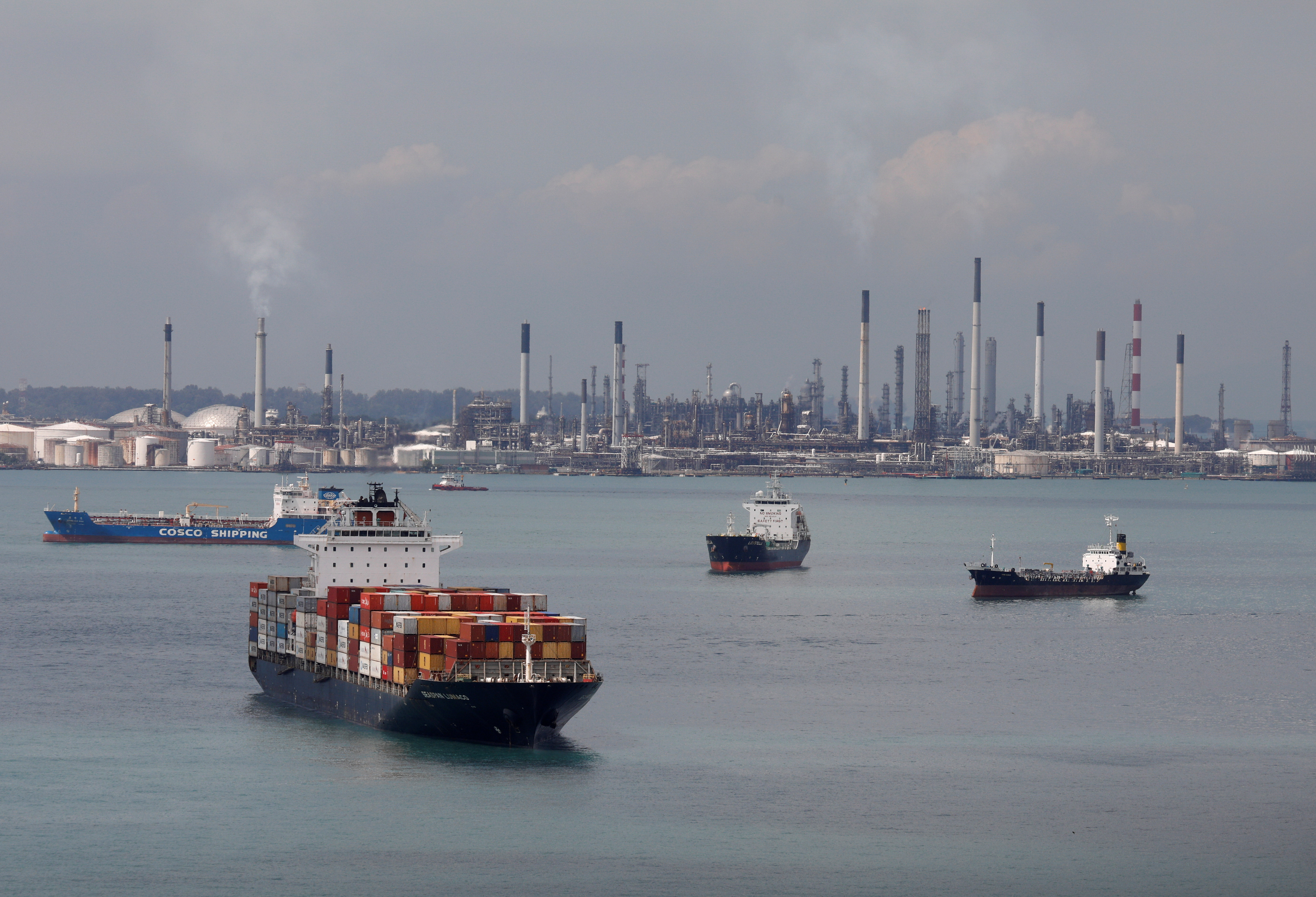 A container ship passes Shell's Pulau Bukom refinery in Singapore
