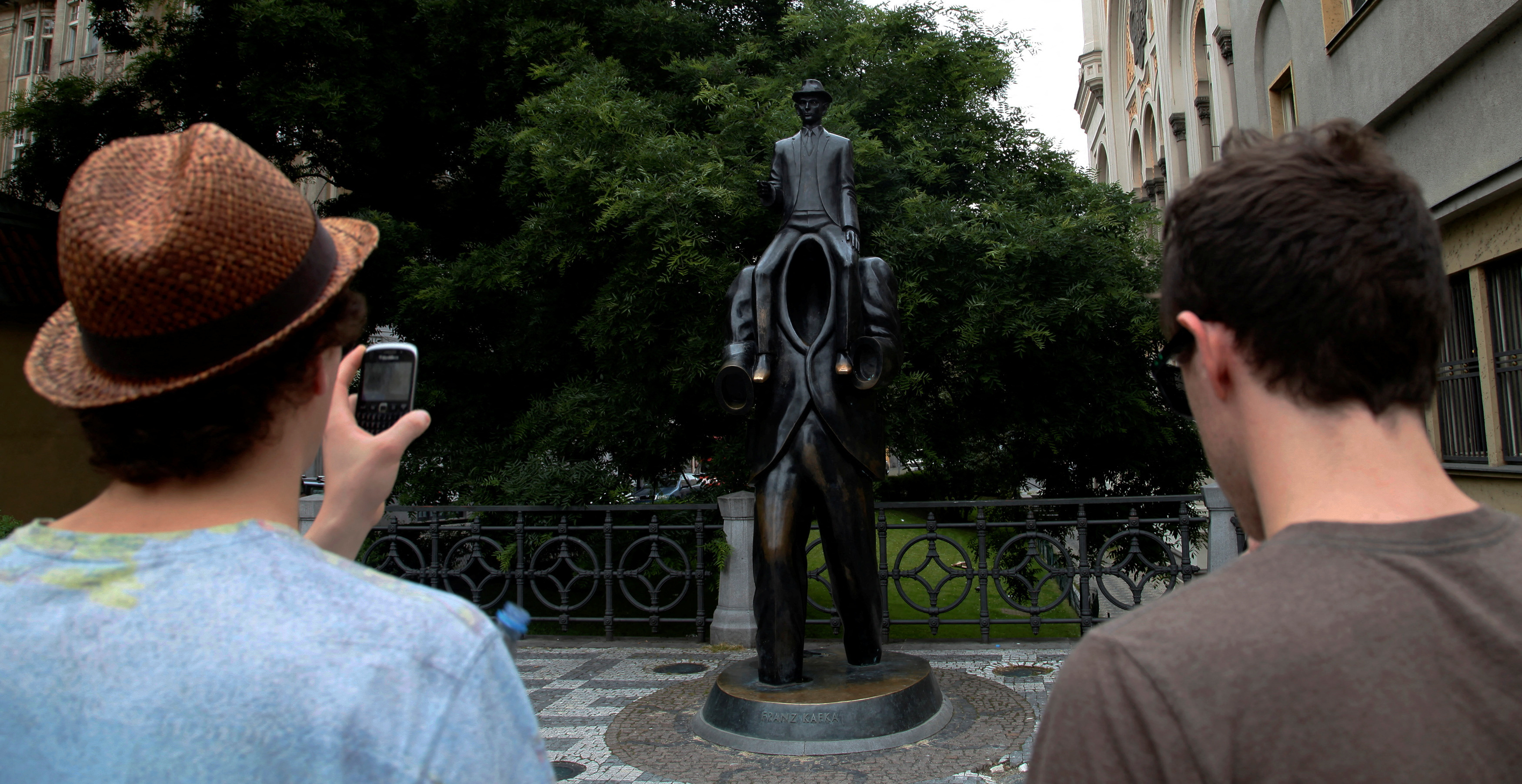 Tourists look at a statue of famous German-language writer Franz Kafka in central Prague, on the day marking the 130th anniversary of his birth