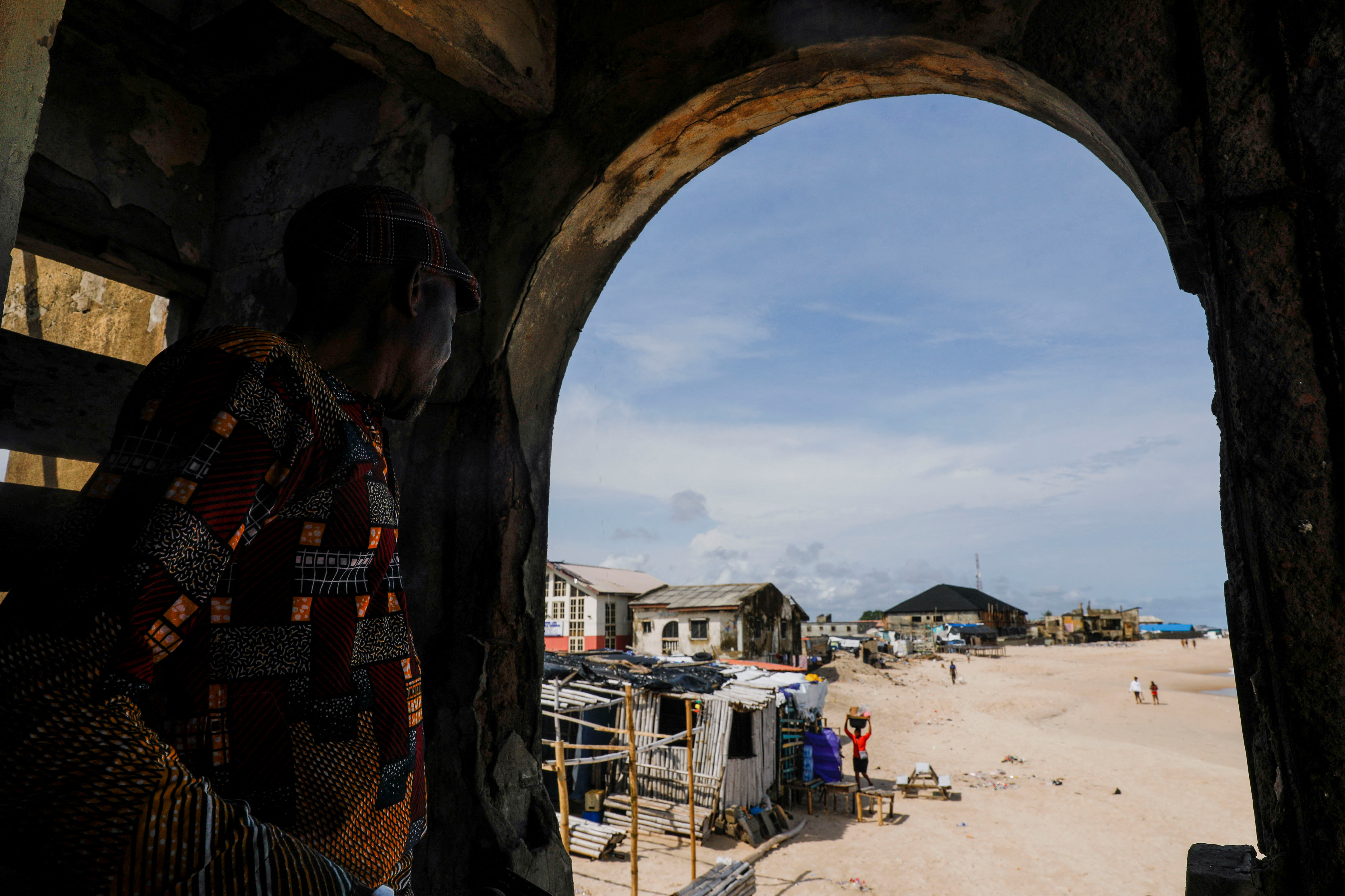 A man looks through a view at the Alpha beach, affected by an ocean surge, in Lagos