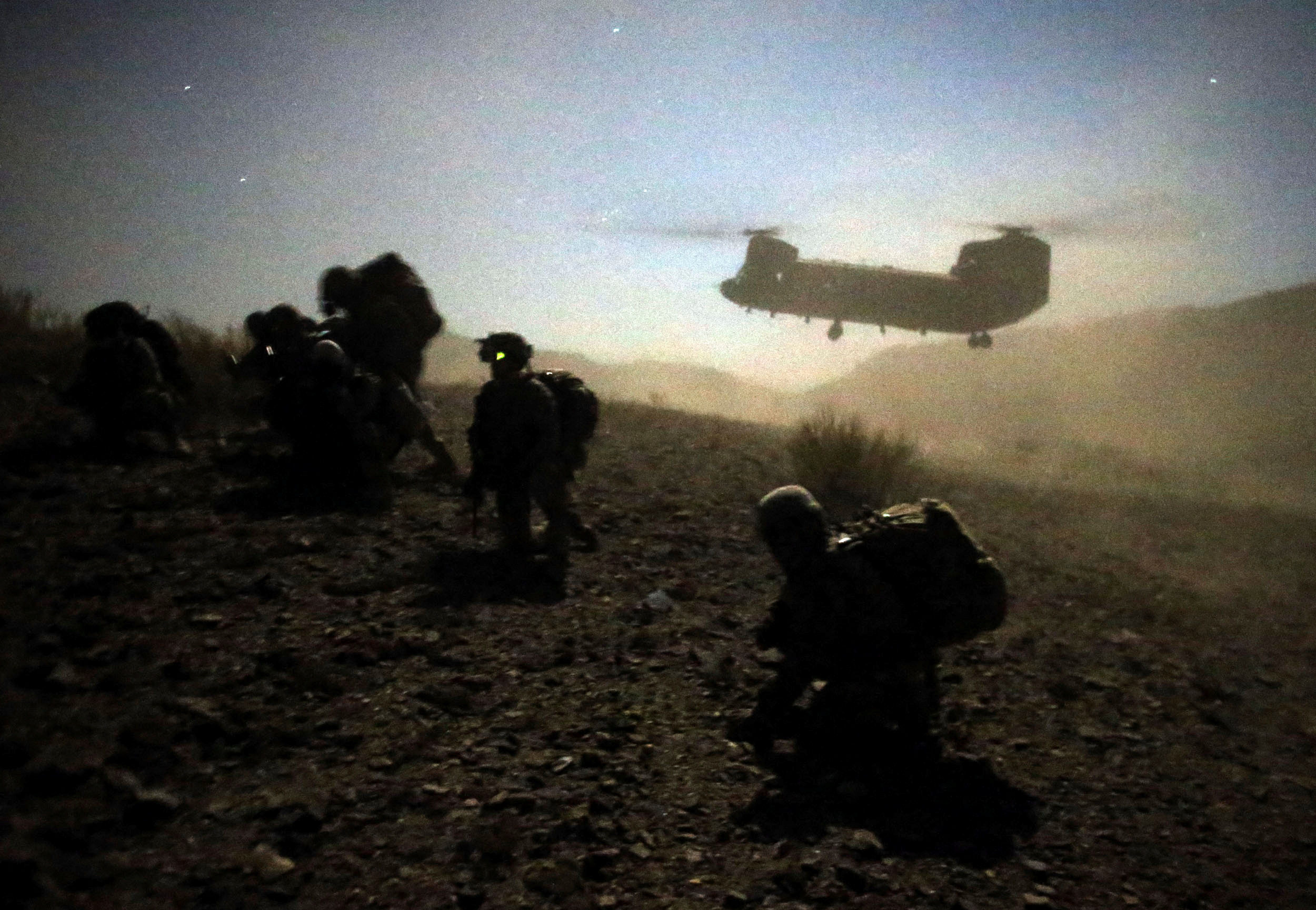 U.S. and Afghan soldiers take a knee near a U.S. Army Chinook during an operation near the town of Walli Was in Paktika province