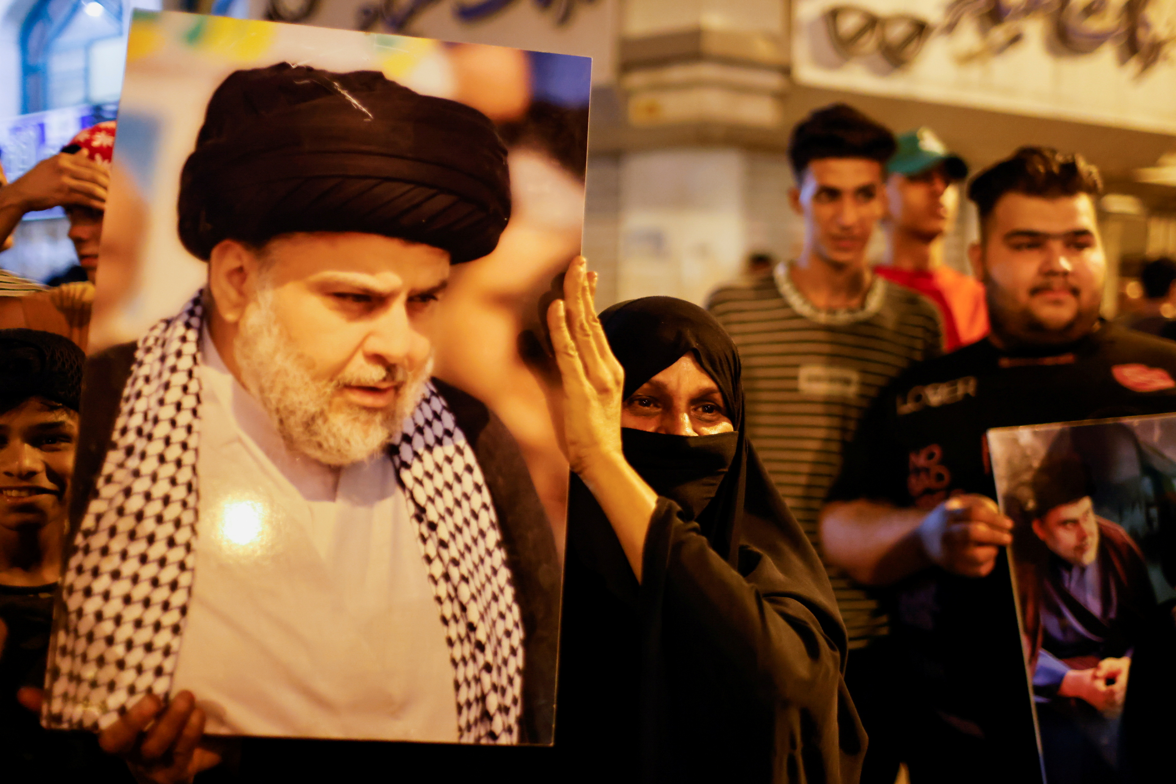 A woman holds a picture of Sadr's movement leader Moqtada al-Sadr, as his supporters celebrate after preliminary results of Iraq's parliamentary election were announced in Baghdad, Iraq October 11, 2021. REUTERS/Thaier Al-Sudani/File Photo