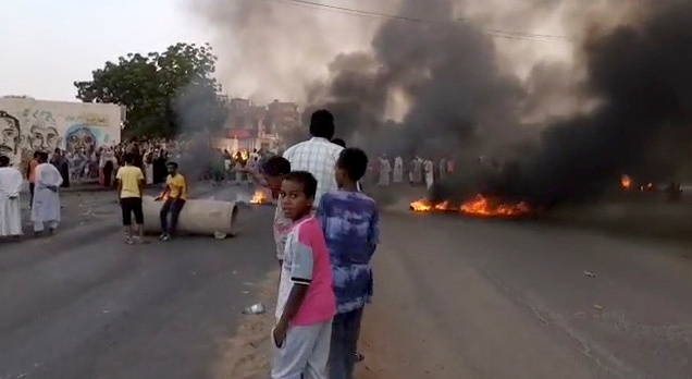 People gather around as smoke and fire are seen on the streets of Kartoum, Sudan, amid reports of a coup, October 25, 2021, in this still image from video obtained via social media. RASD SUDAN NETWORK via REUTERS 