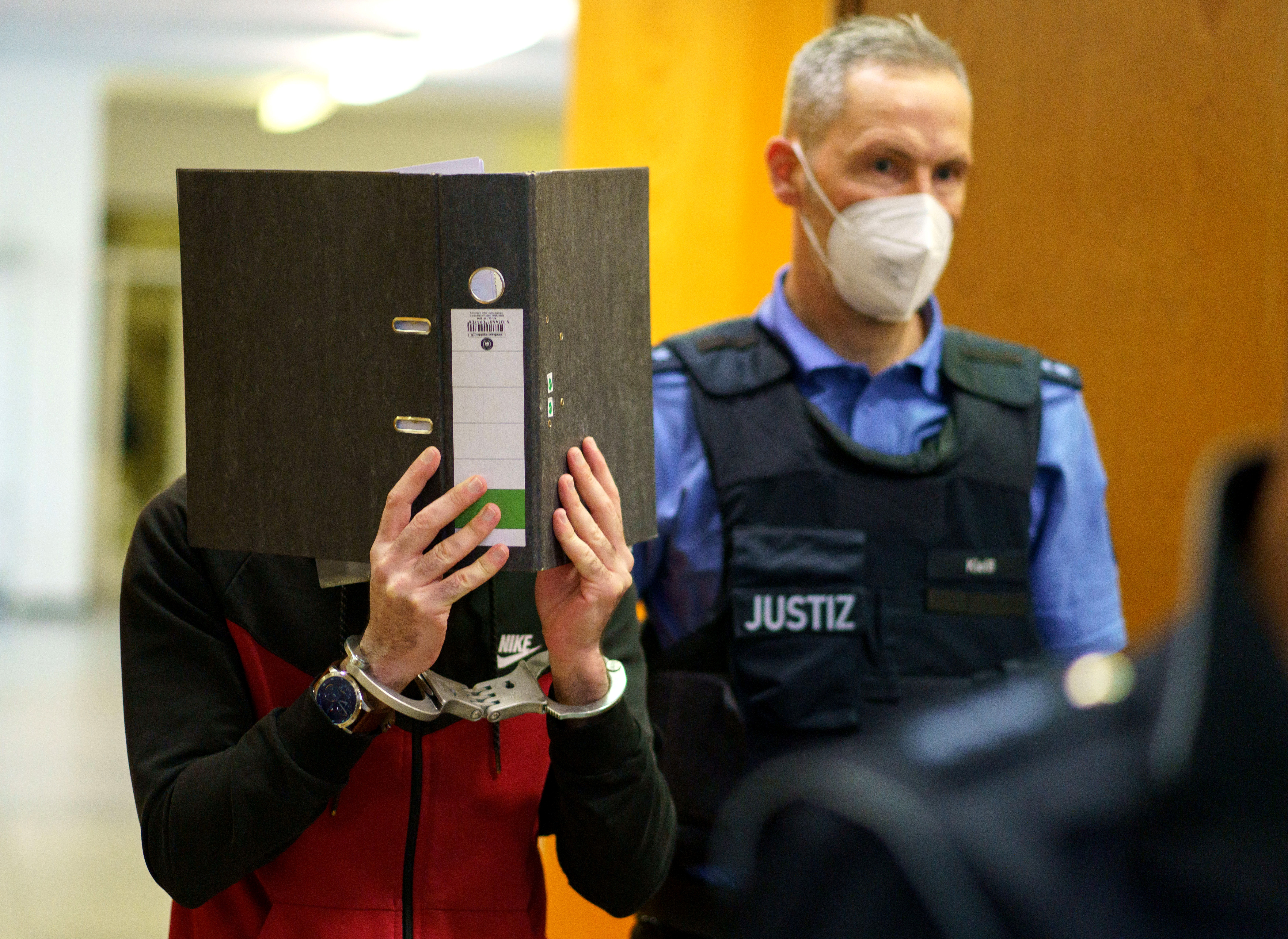 Iraqi defendant Taha Al-J. covers his face as he arrives before his verdict in a courtroom in Frankfurt, Germany, November 30, 2021.        Frank Rumpenhorst/Pool via REUTERS