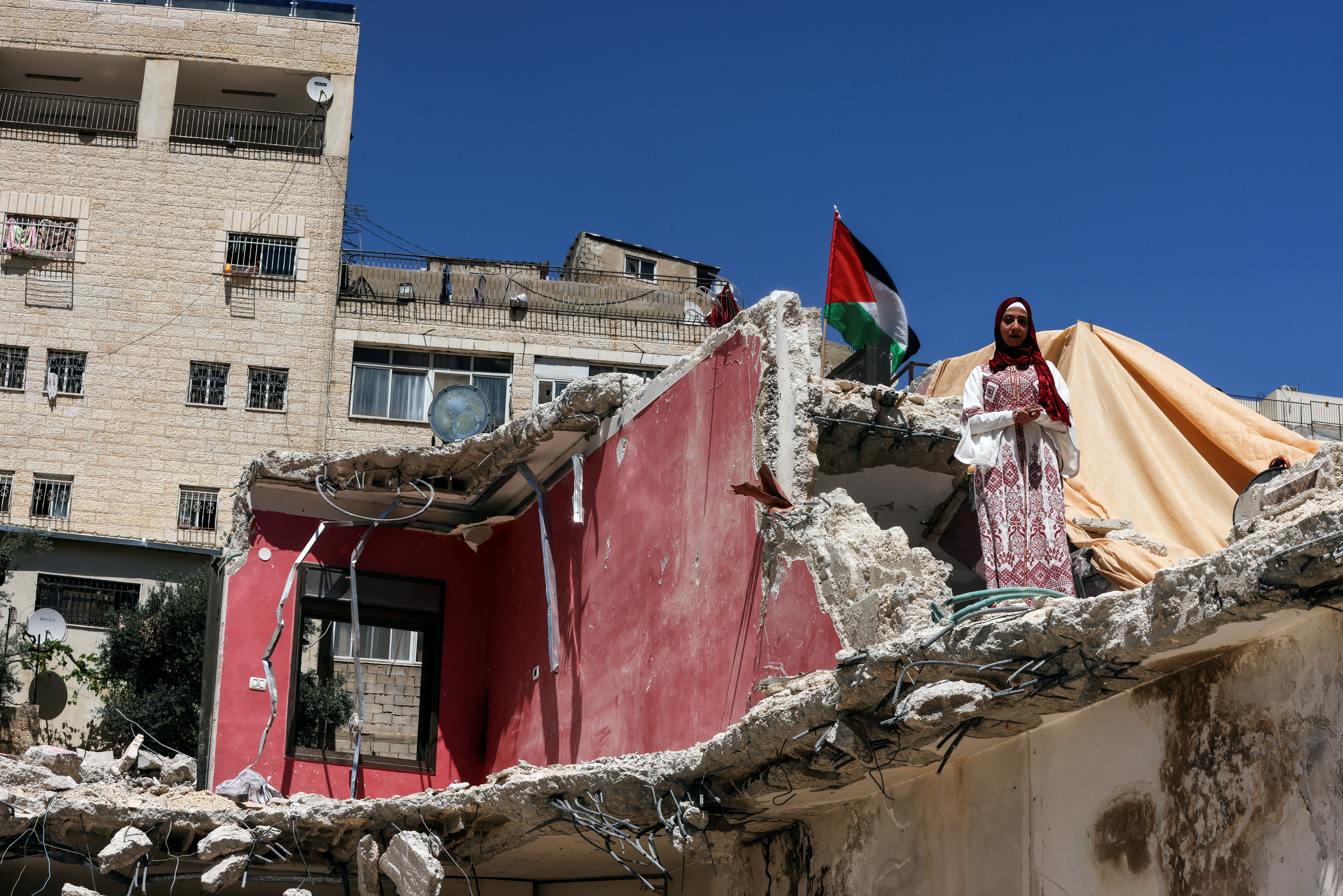 Palestinian bride Rabeha Al-Rajabi stands on the debris her house, that was partly demolished by Israeli authority, as part of her pre-wedding ceremony in East Jerusalem