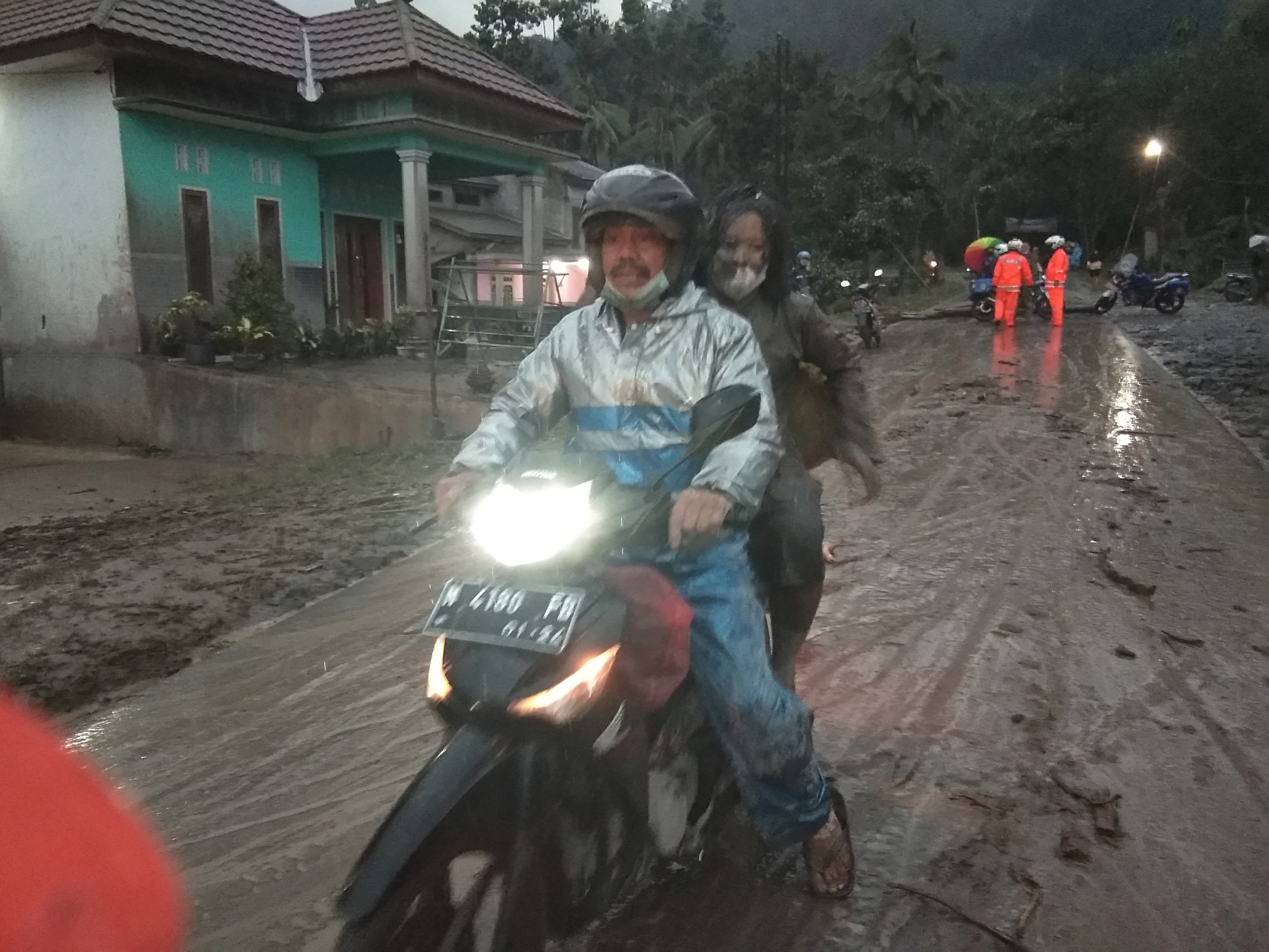 People ride a motorbike on a road that is covered with volcanic ash following an eruption of the Semeru mount volcano at Sumberwuluh village