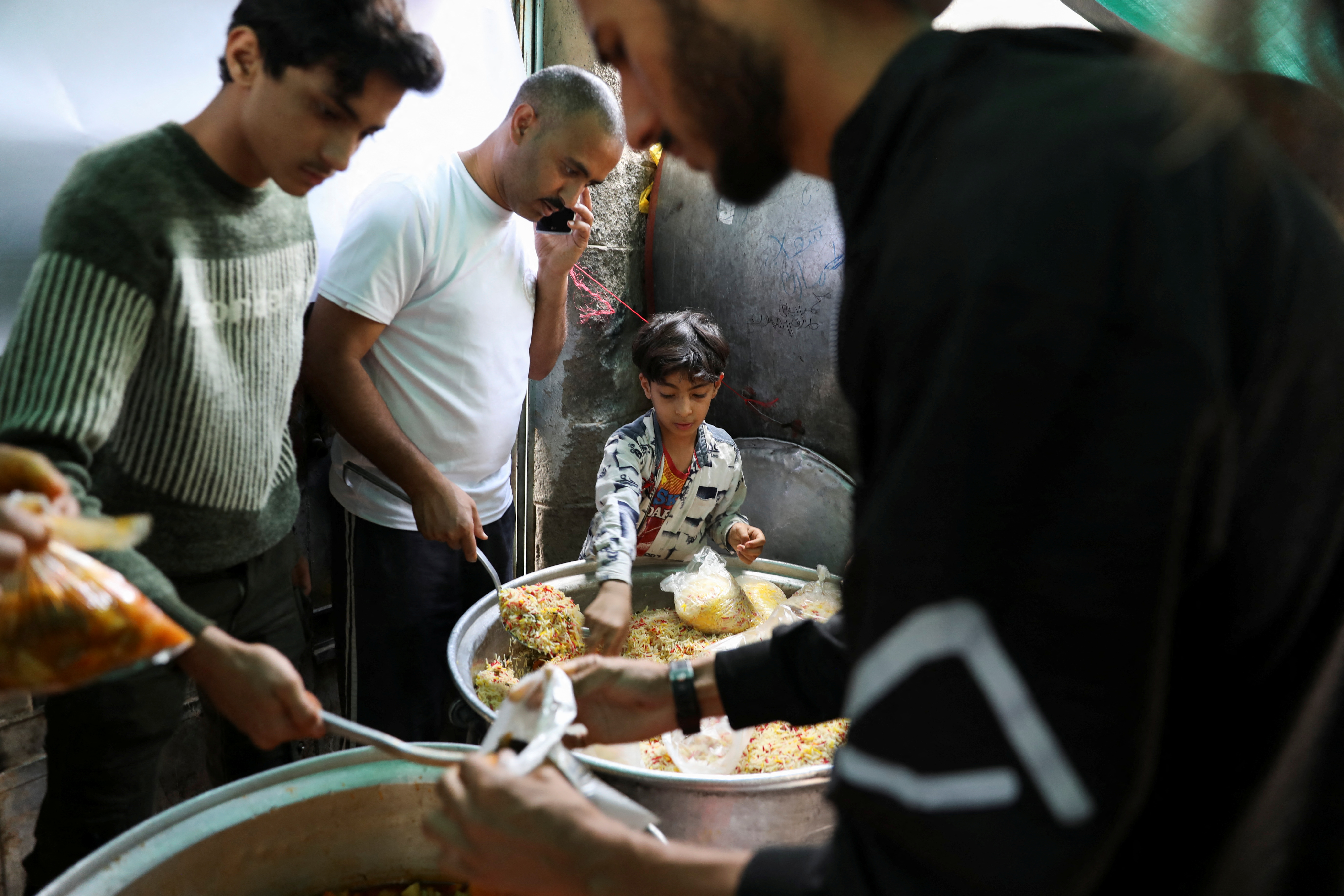 Boy helps volunteers to prepare meals to be distributed at a charity kitchen during the holy month of Ramadan in Sanaa