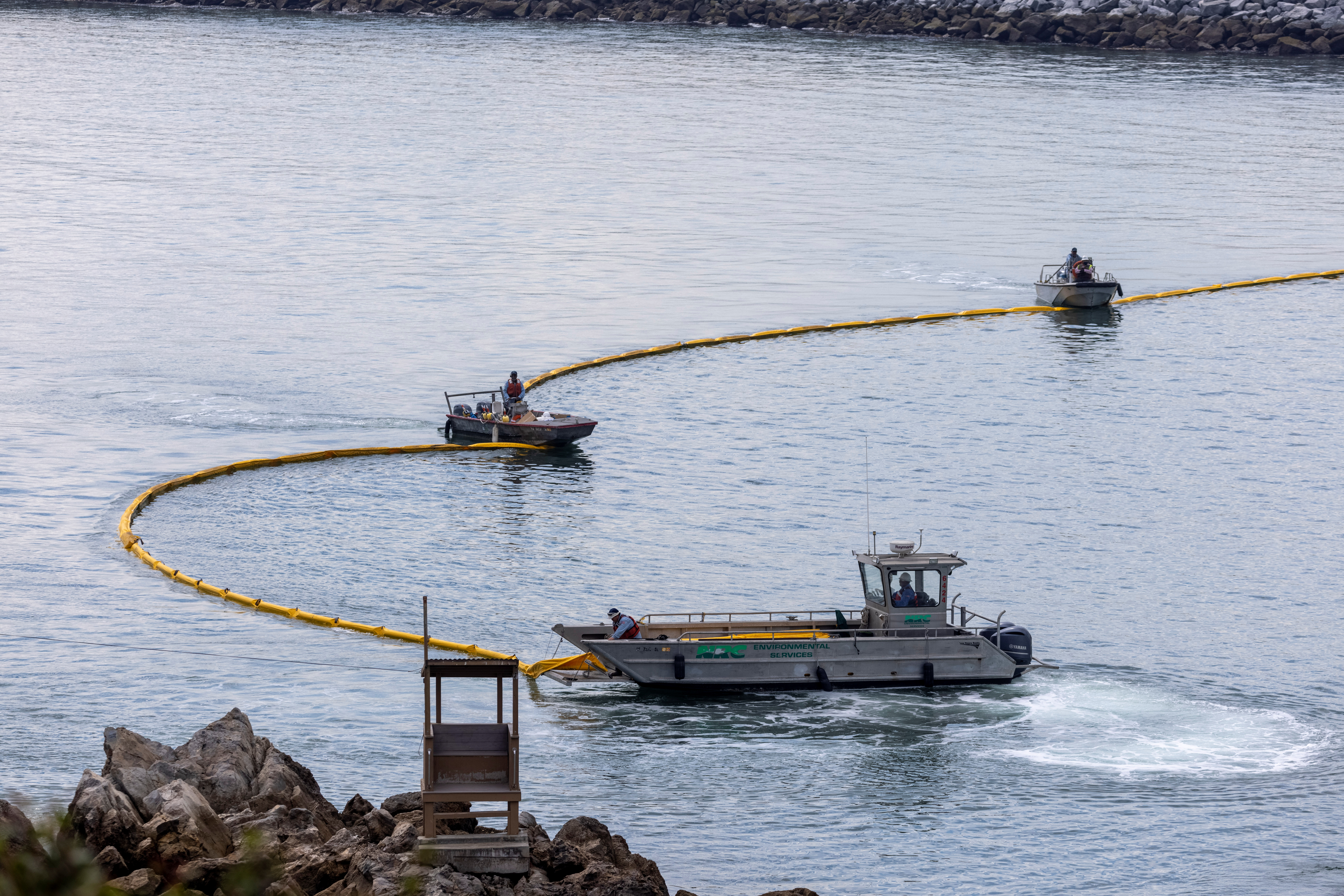 Workers seal off Newport Beach harbor as a major California oil spill moves south down the coast