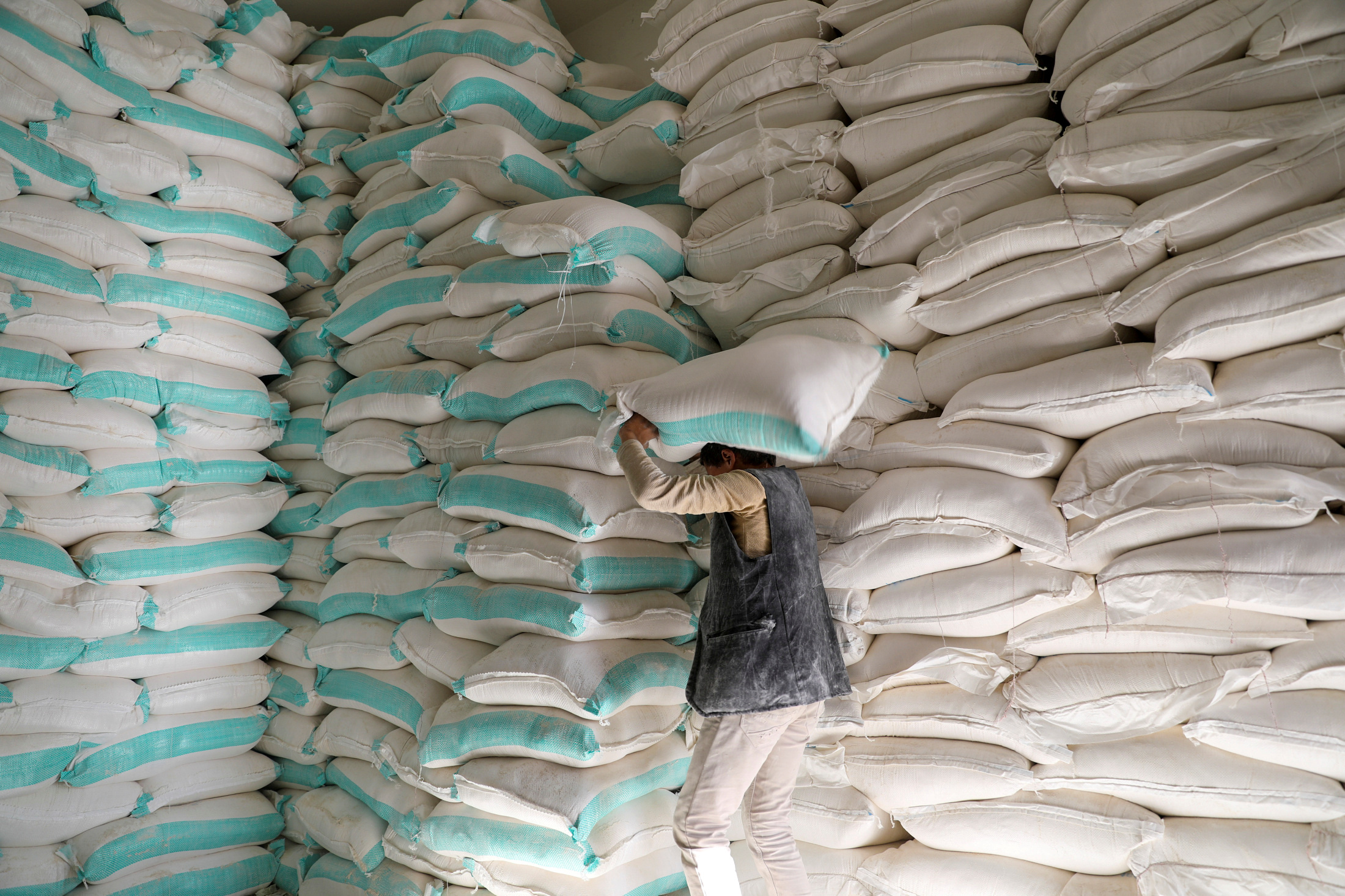 A worker carries a sack of wheat flour at a World Food Programme food aid distribution center in Sanaa
