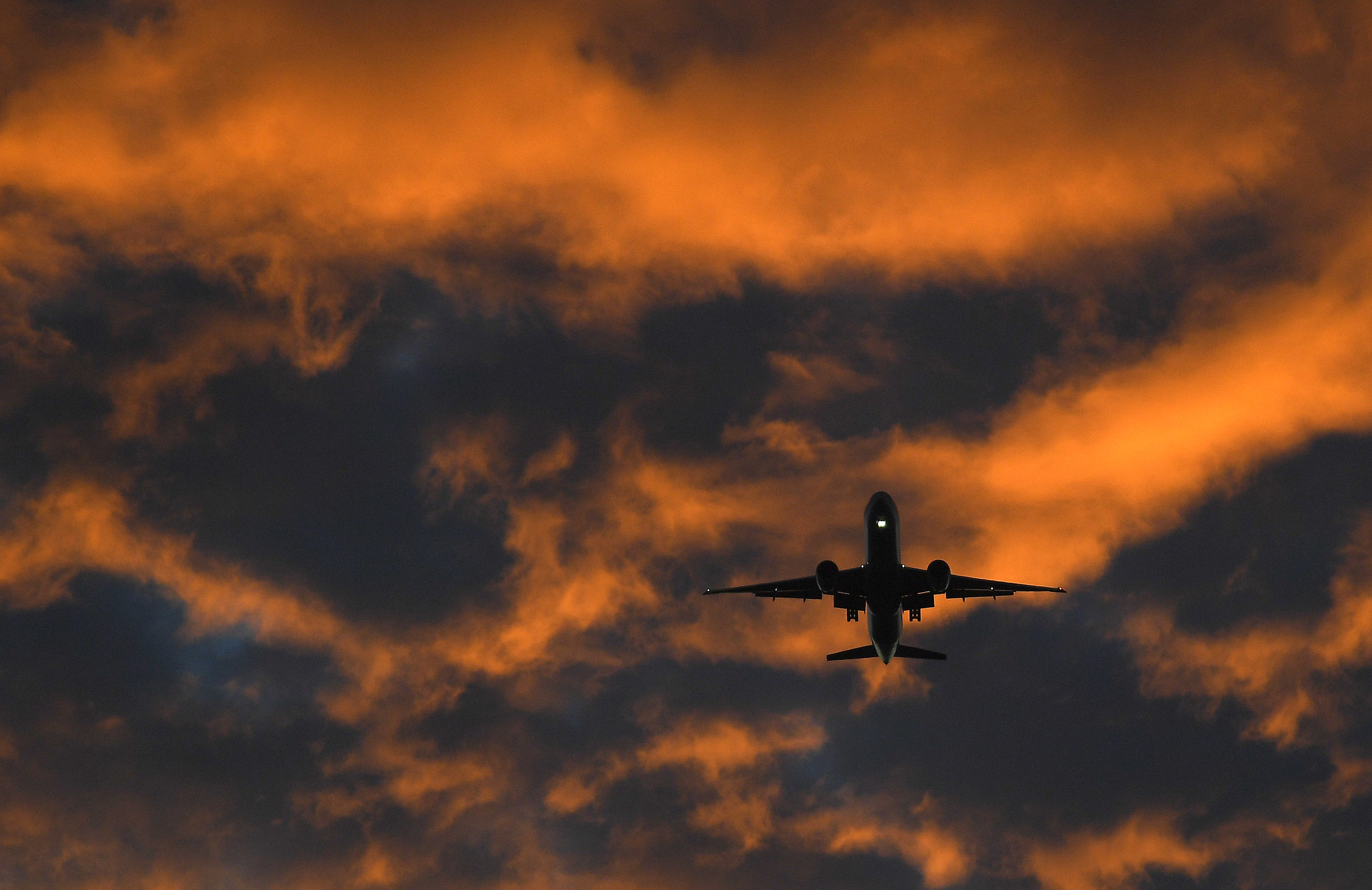 A passenger plane flies towards Heathrow airport at dawn in London, Britain