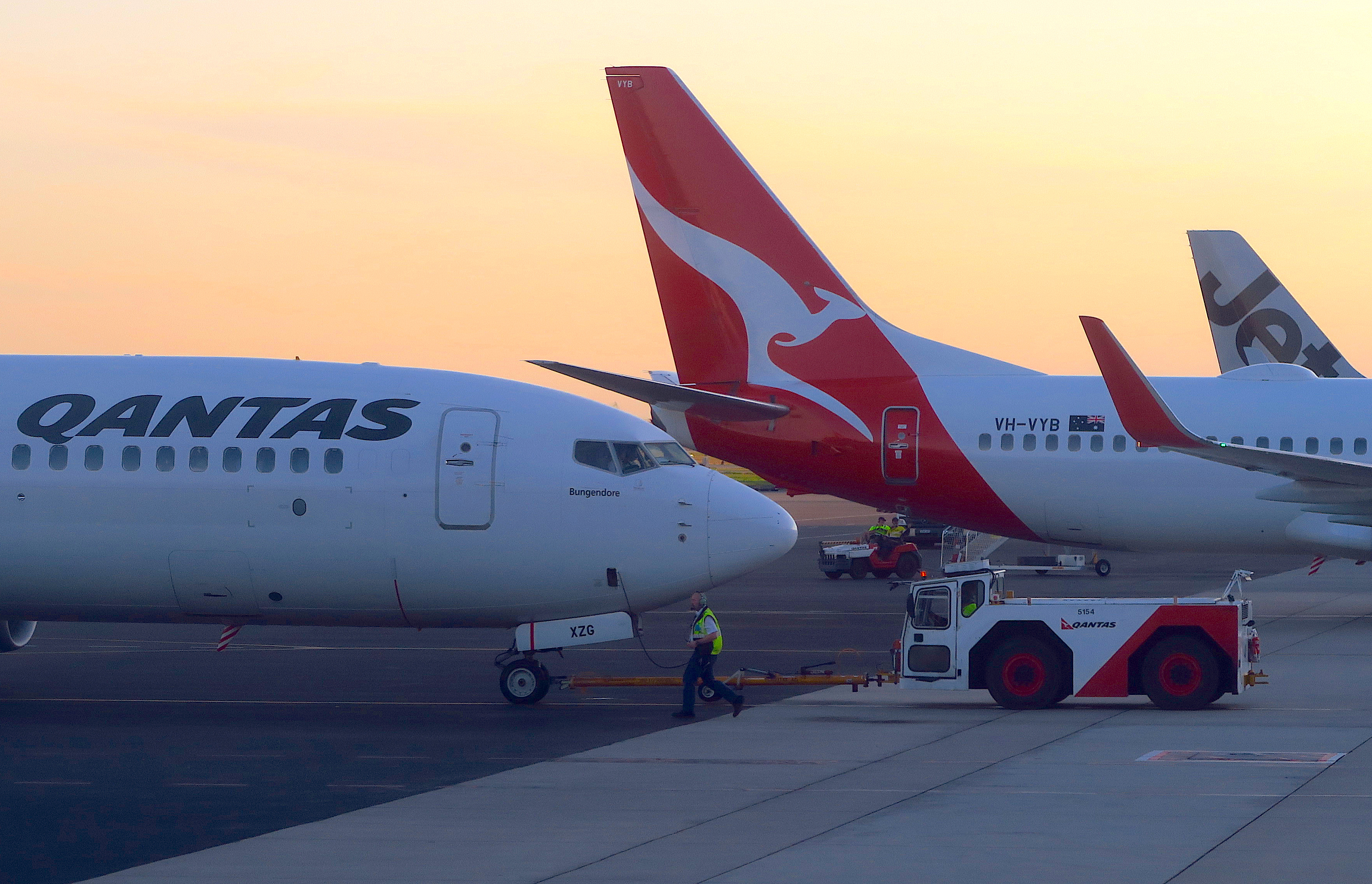 Workers are seen near Qantas Airways, Australia's national carrier, Boeing 737-800 aircraft on the tarmac at Adelaide Airport
