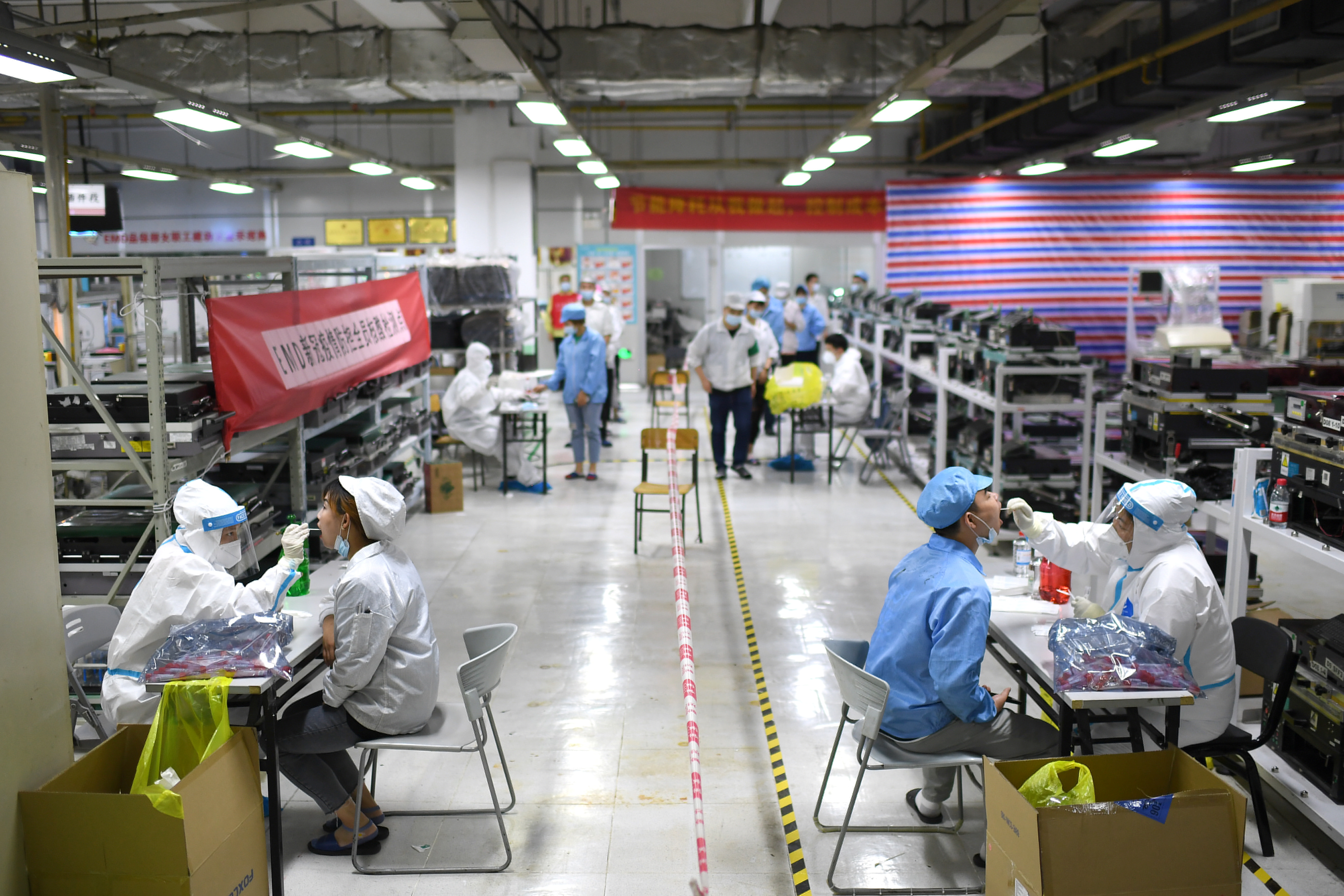 Medical workers collect swabs from workers for nucleic acid testing at a Foxconn factory, following new COVID-19 cases in Wuhan