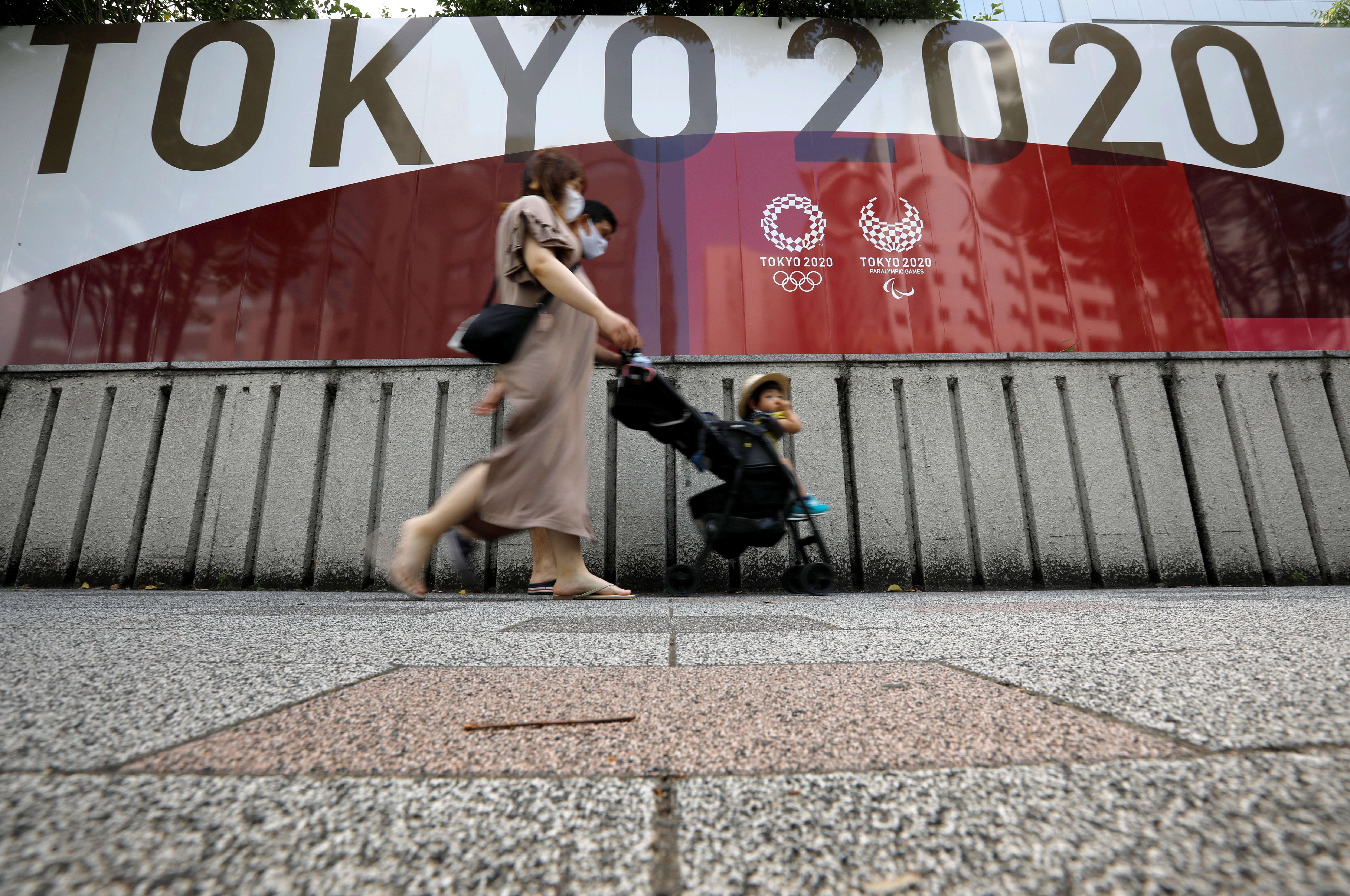 A family walks past an advertisement for Tokyo 2020 Olympic and Paralympic Games