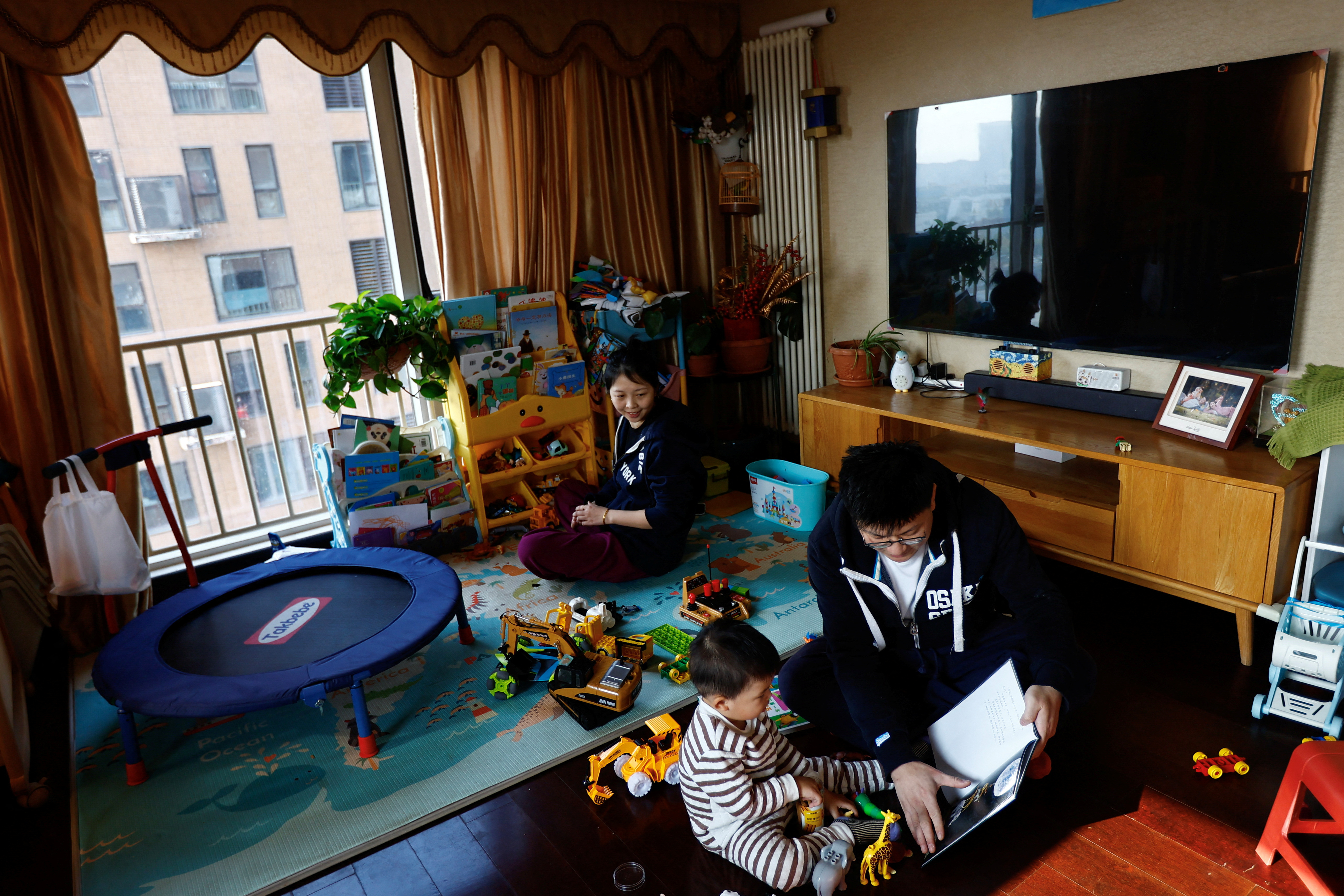 Ang Ran, Tang Huajun play with their 2-year-old son Tang Ziang at their home in Beijing