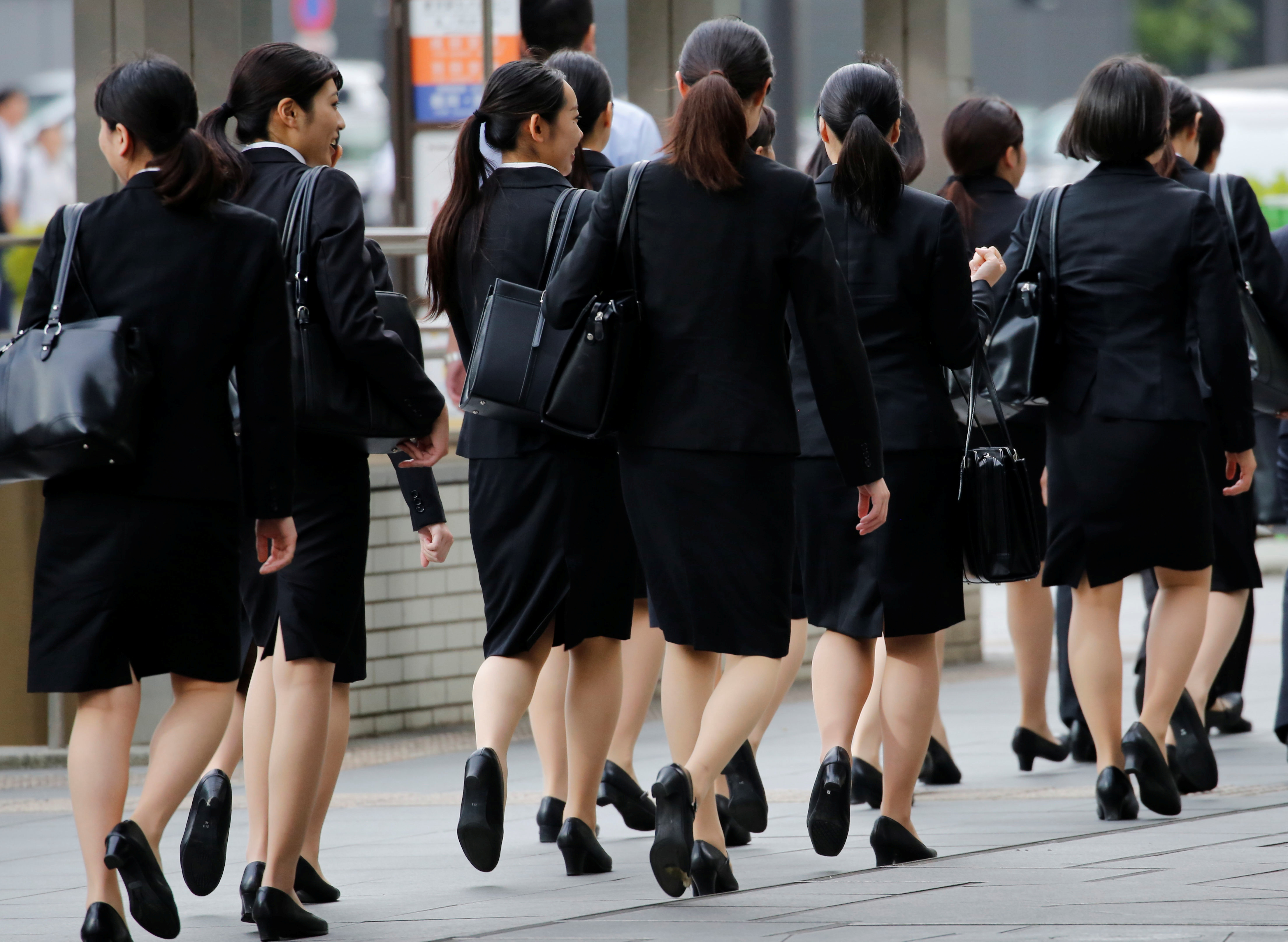 Female office workers wearing high heels, clothes and bags of the same colour make their way at a business district in Tokyo