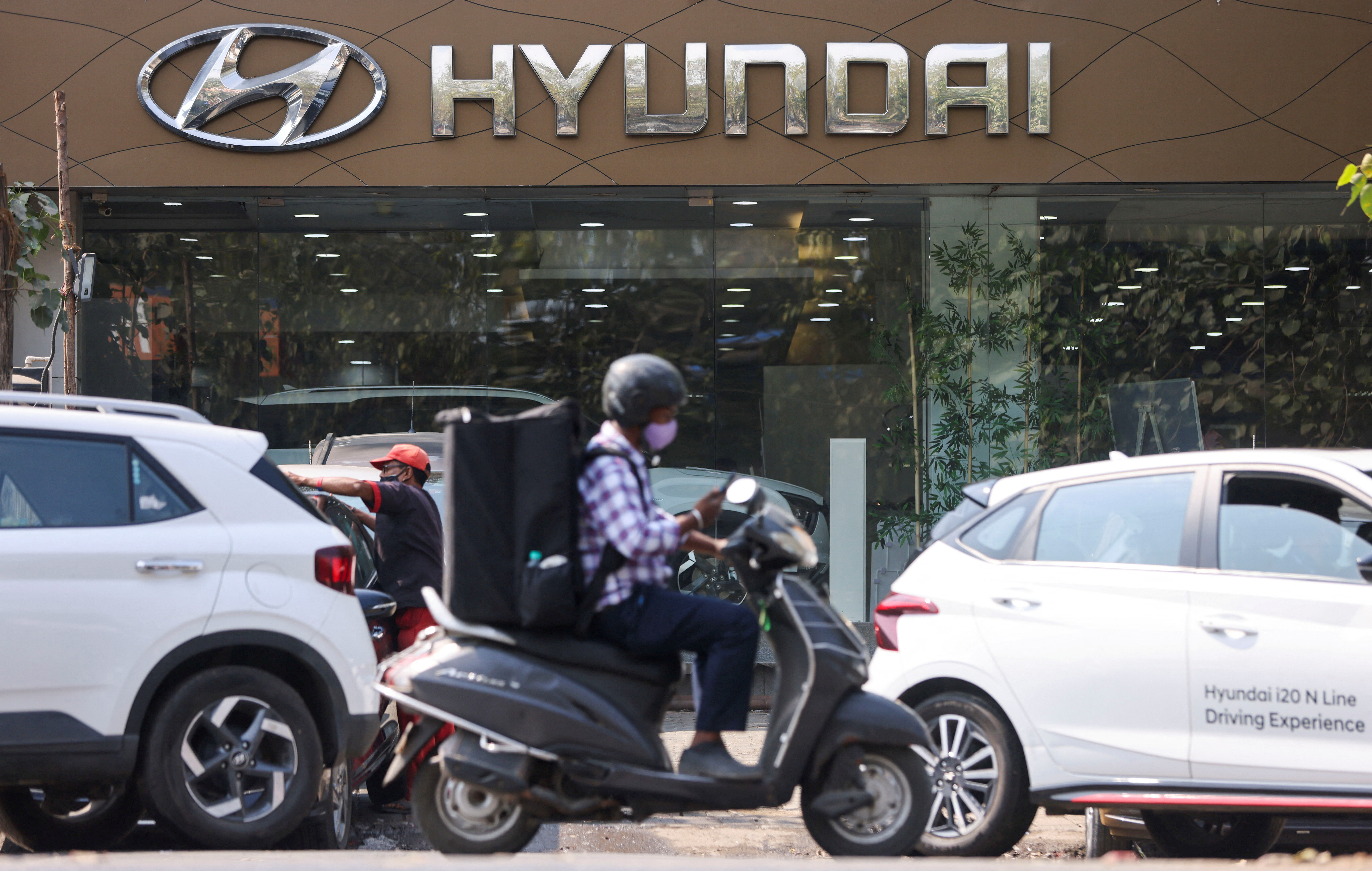 A man rides a scooter past a Hyundai automobile showroom in Mumbai