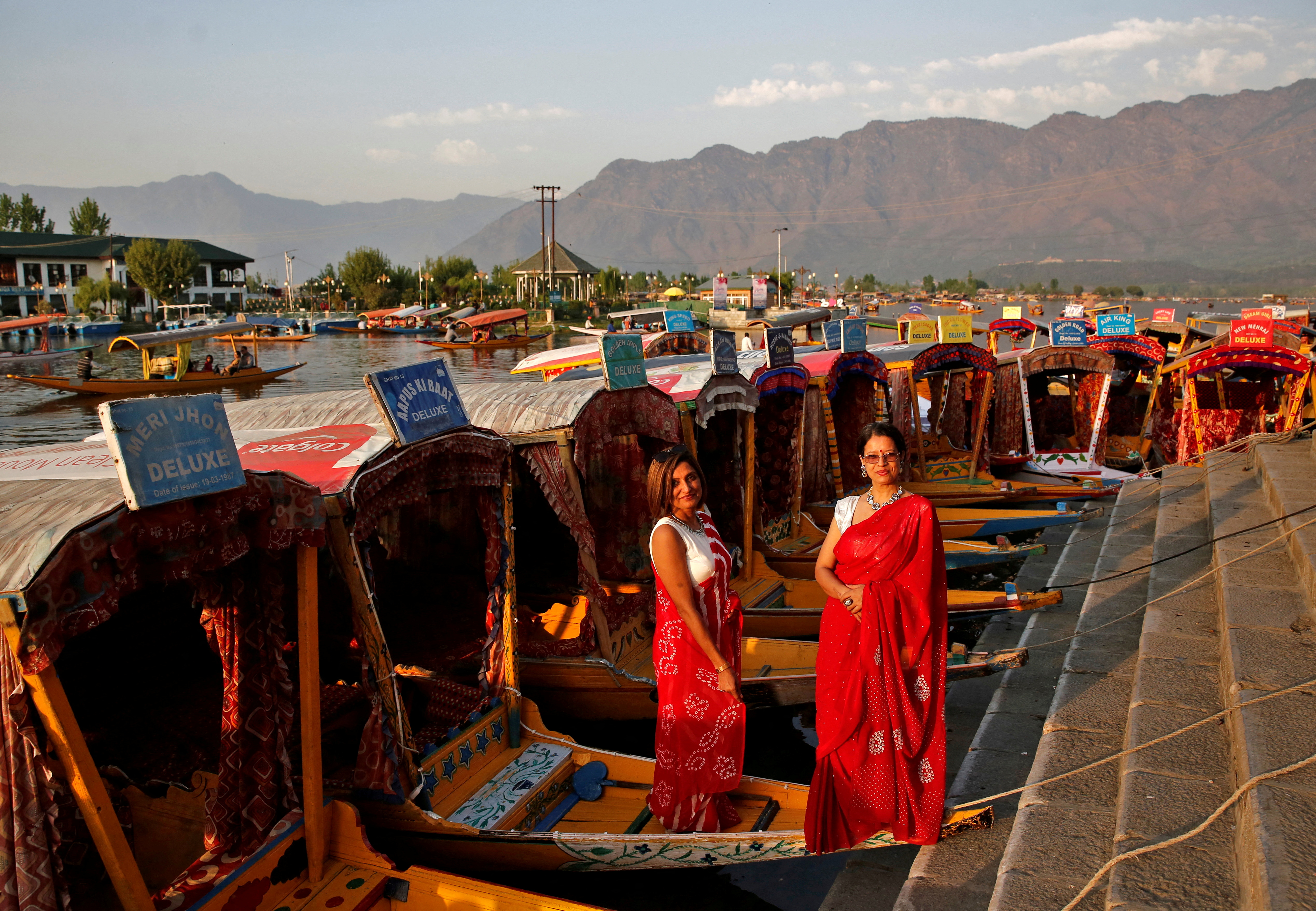Tourists pose on parked "Shikaras" or boats on the banks of Dal Lake in Srinagar